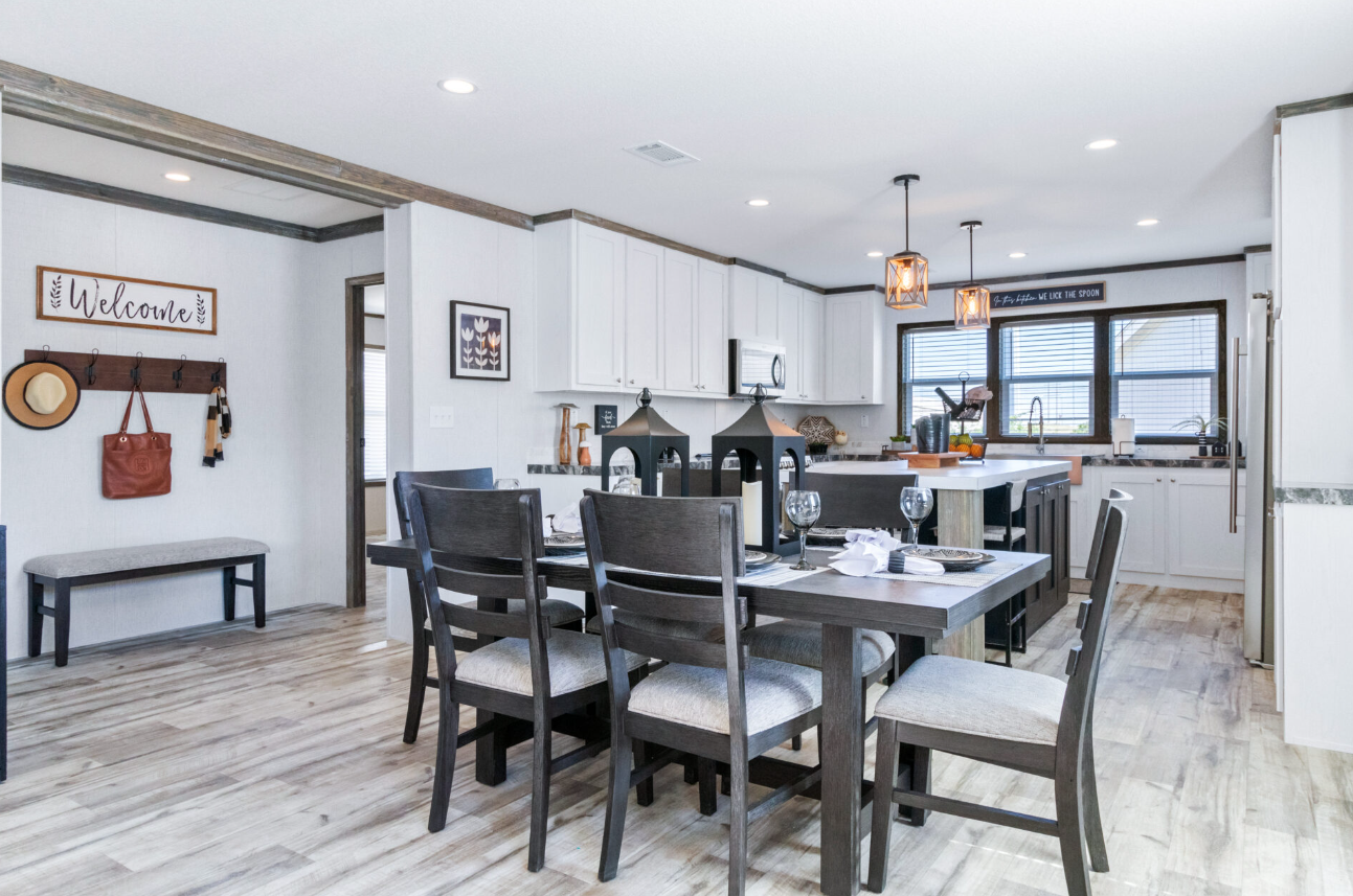 Modern kitchen and dining area with white cabinets, black accents, a wooden dining table set for a meal, and decorative wall art.