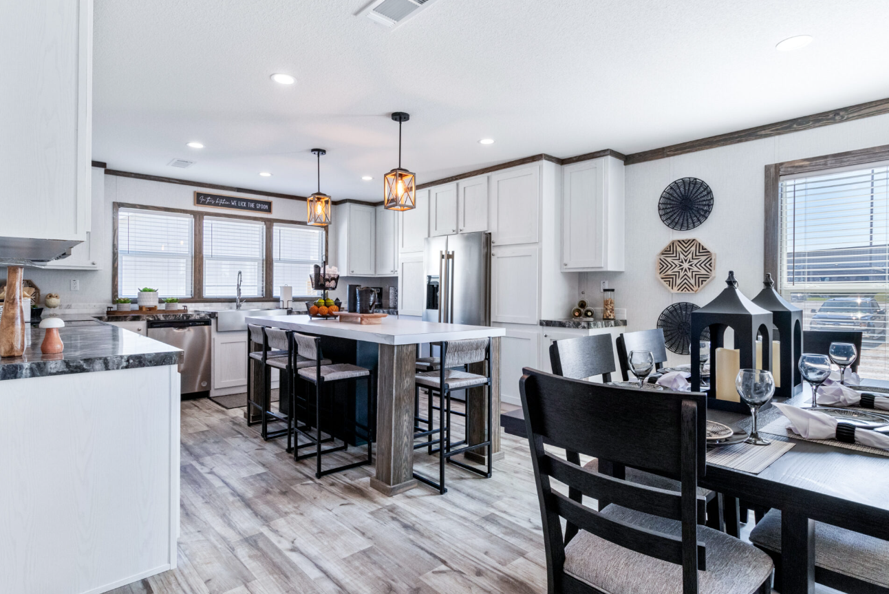 Modern kitchen and dining area with white cabinets, black and wood accents, stainless steel appliances, and a dining table set with glasses and napkins.