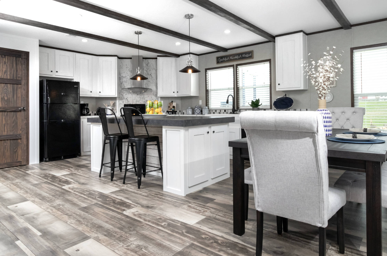 Modern kitchen with white cabinets, black appliances, gray countertops, and a dining area with a dark table and beige upholstered chairs.