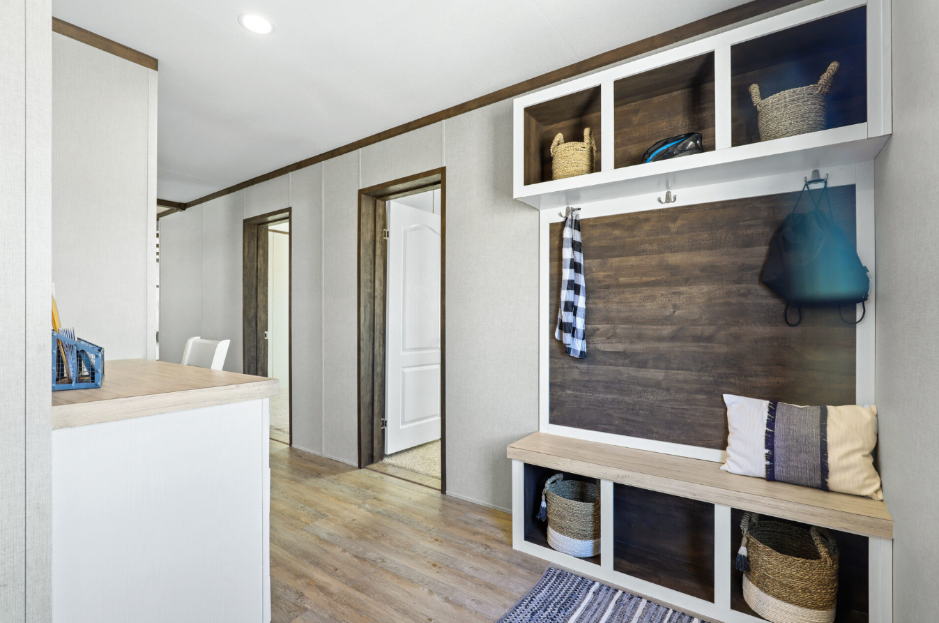 Entryway with built-in wooden bench, baskets, hooks, and wall cubbies in a modern home.