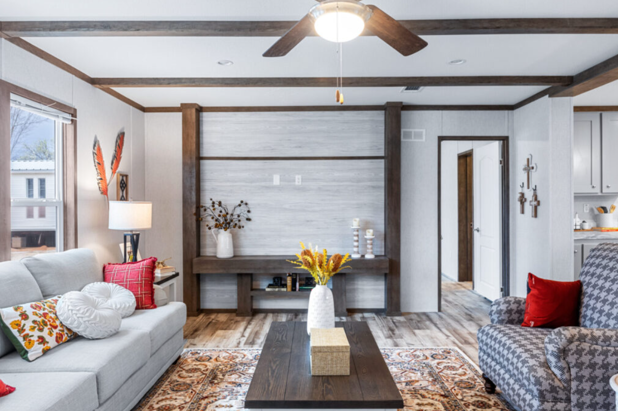 Living room with a white sofa, patterned armchair, wooden coffee table, and decorative accents including vases, pillows, and wall art.