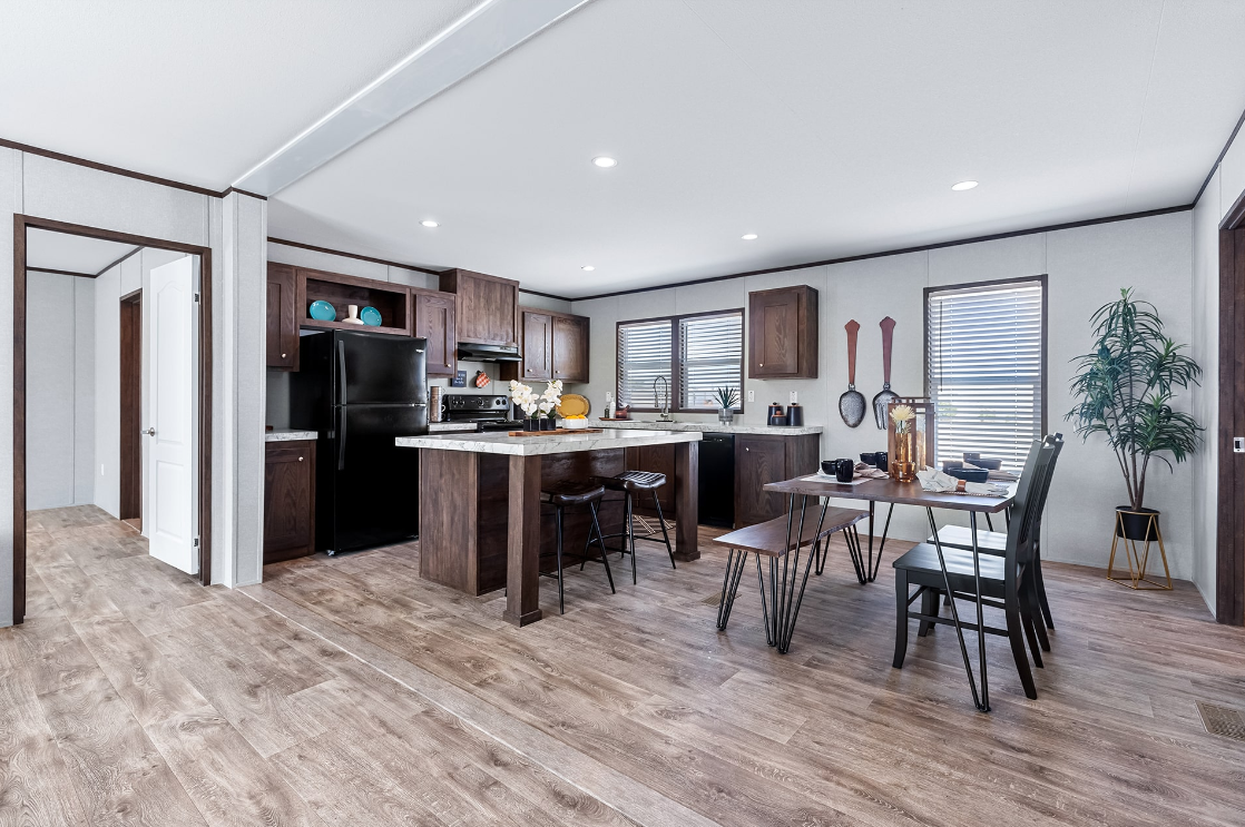 Kitchen and dining area with dark wood cabinets, black appliances, a marble island, a small dining table with chairs, and a potted plant in the corner.