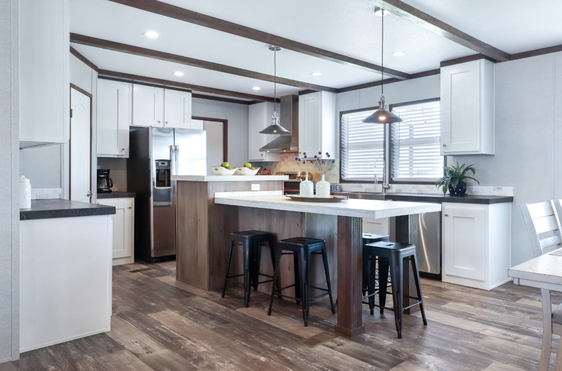 Modern kitchen with white cabinets, black countertops, wooden accents, a central island with three black stools, stainless steel appliances, and a window with horizontal blinds.