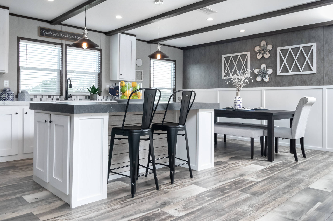 Modern kitchen and dining area with white cabinetry, gray countertops, black chairs, and decorative wall art.
