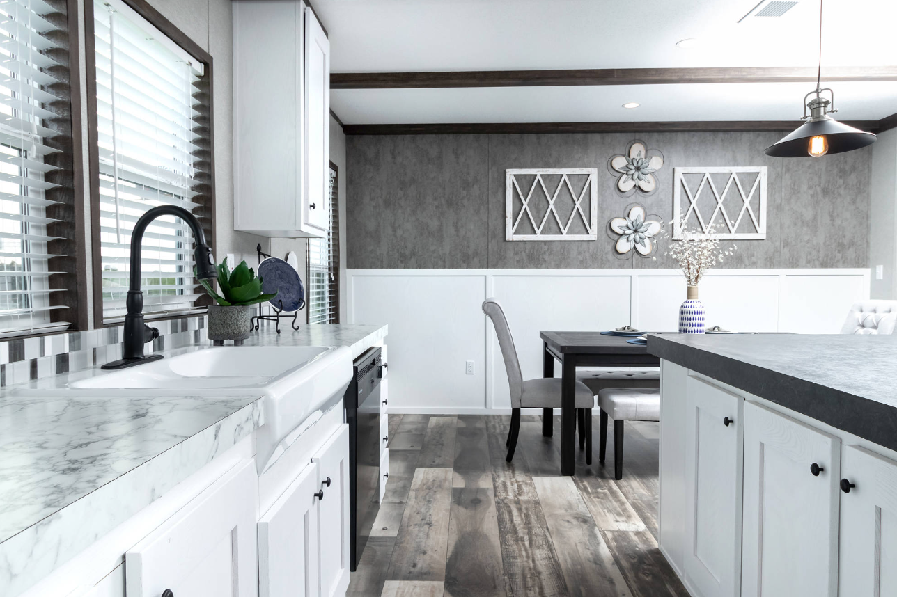 Modern kitchen and dining area with white cabinets, marble countertop, black faucet, gray wall, and wall art with flowers
