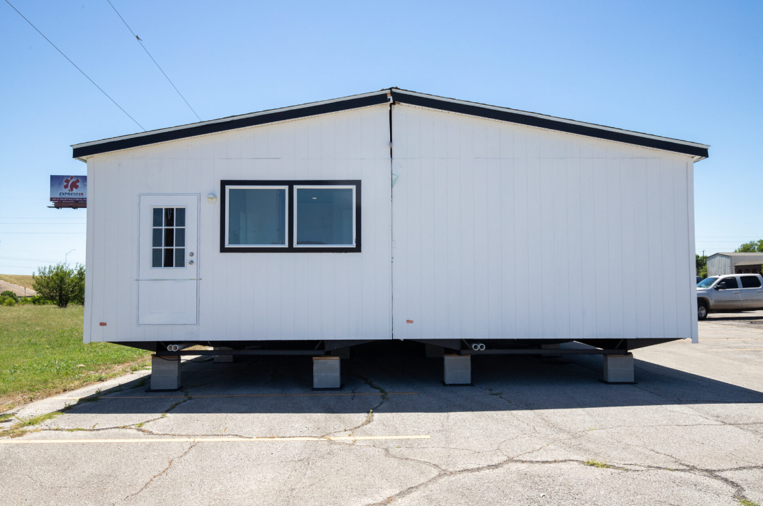 White mobile home elevated on concrete blocks in a parking area