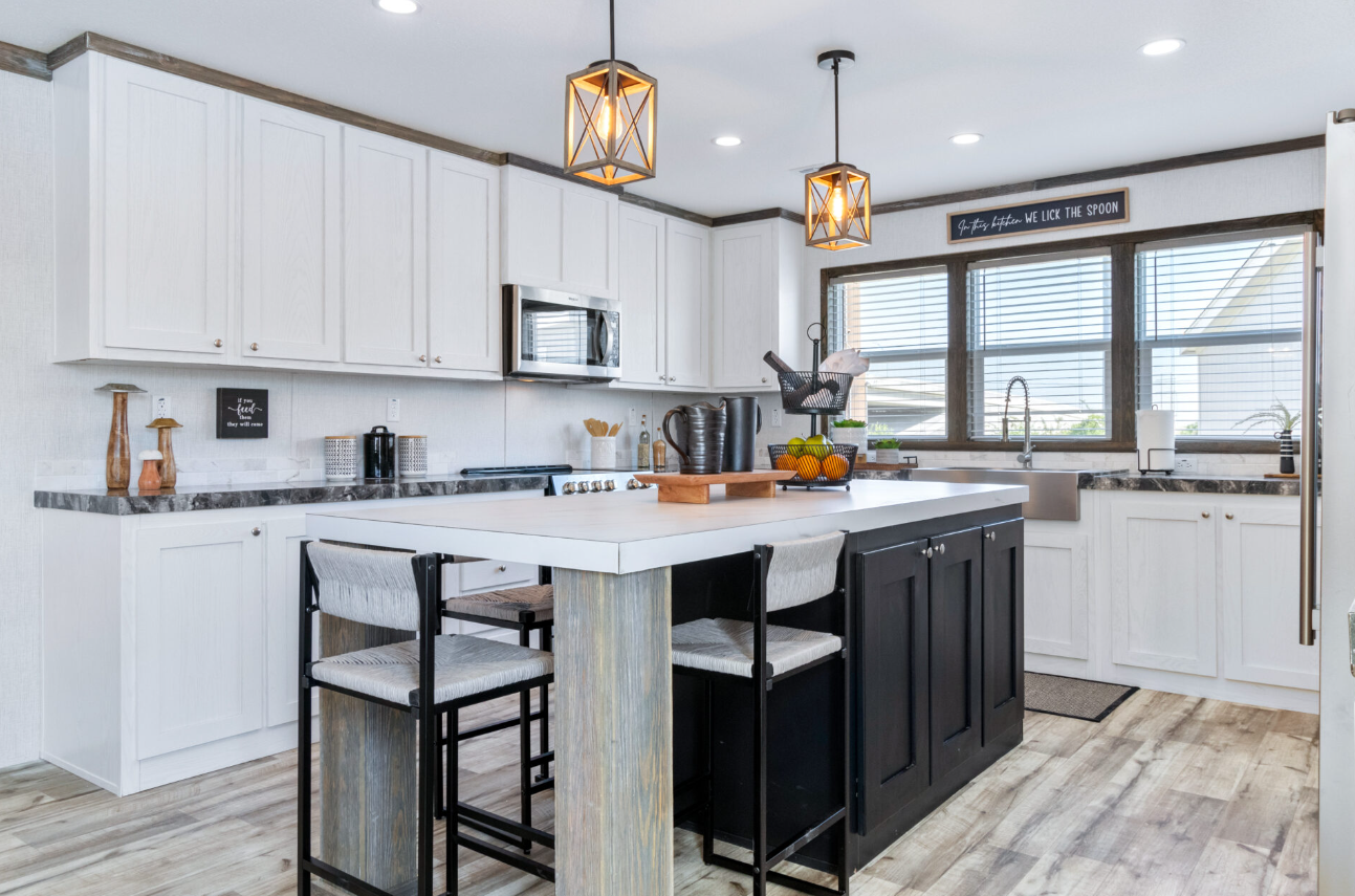Modern kitchen with white cabinets, black and white island, wooden accents, and pendant lighting