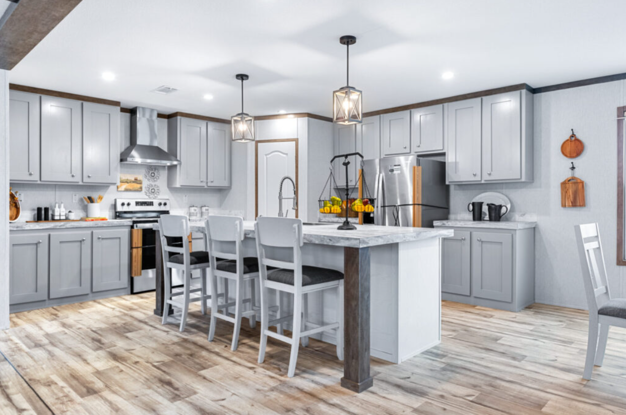Modern kitchen with light gray cabinets, stainless steel appliances, a marble island, and wooden flooring, illuminated by pendant pendant lights.