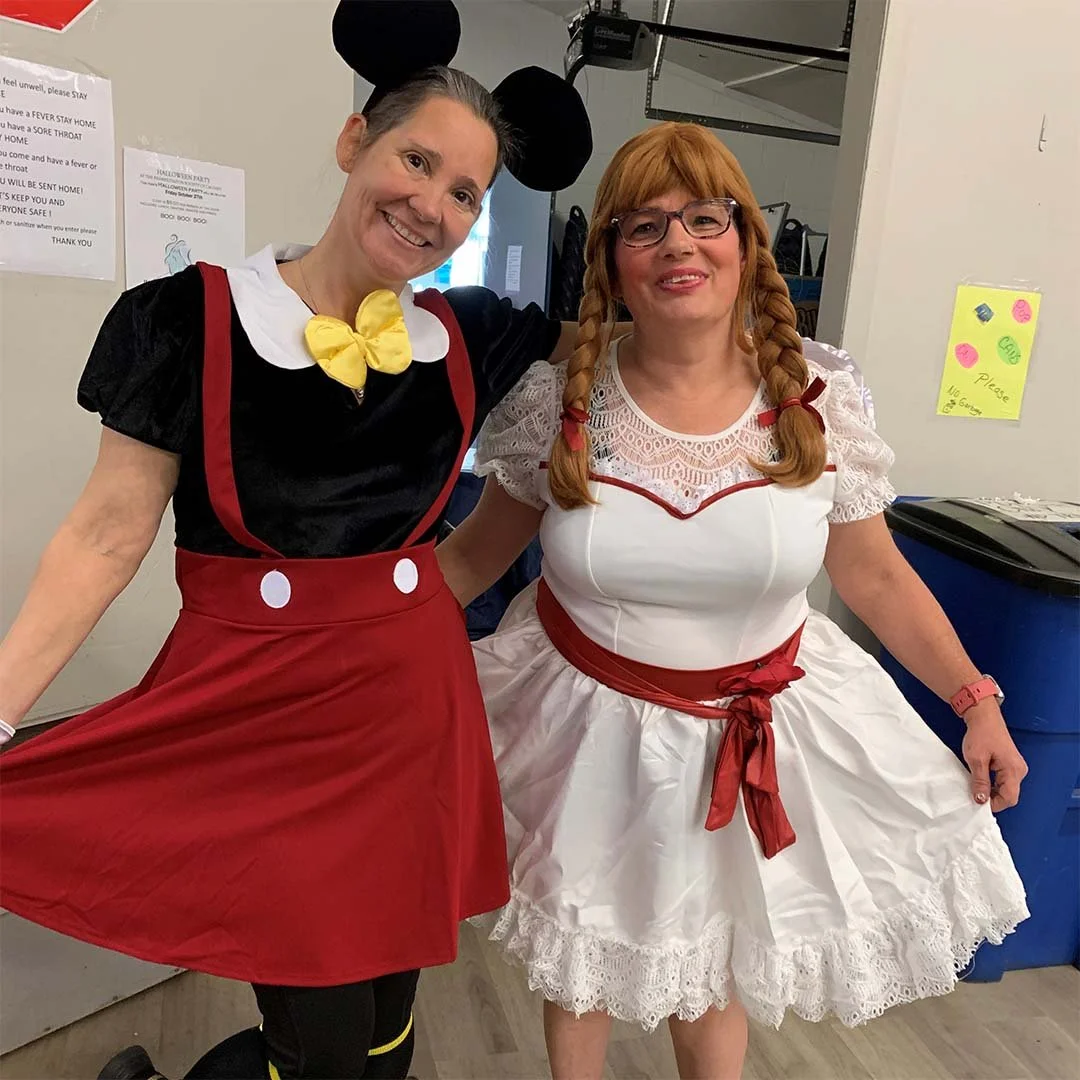 Two members dressed up in costumes smile and pose for the camera