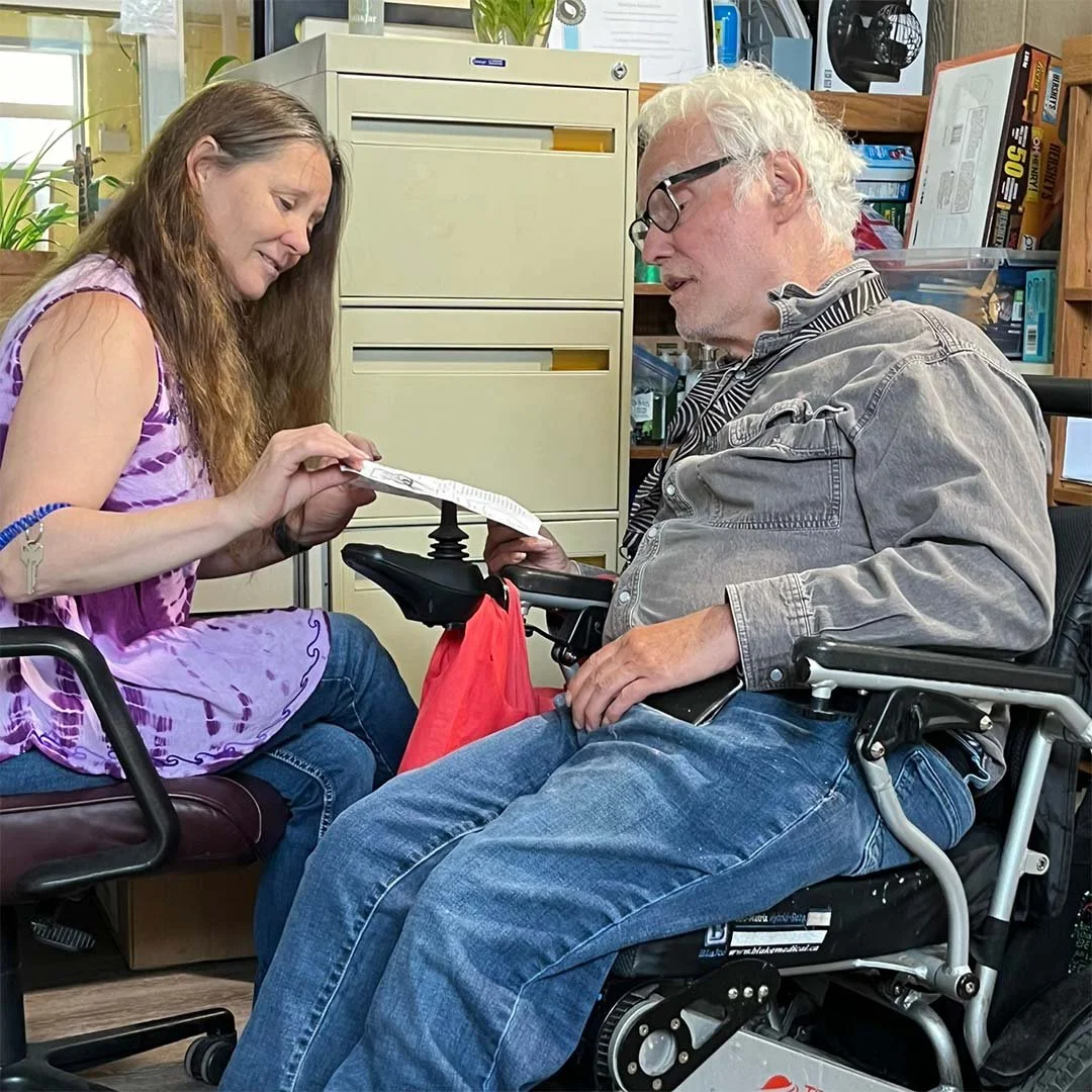 Two community members go over paperwork together in a bright office with plants