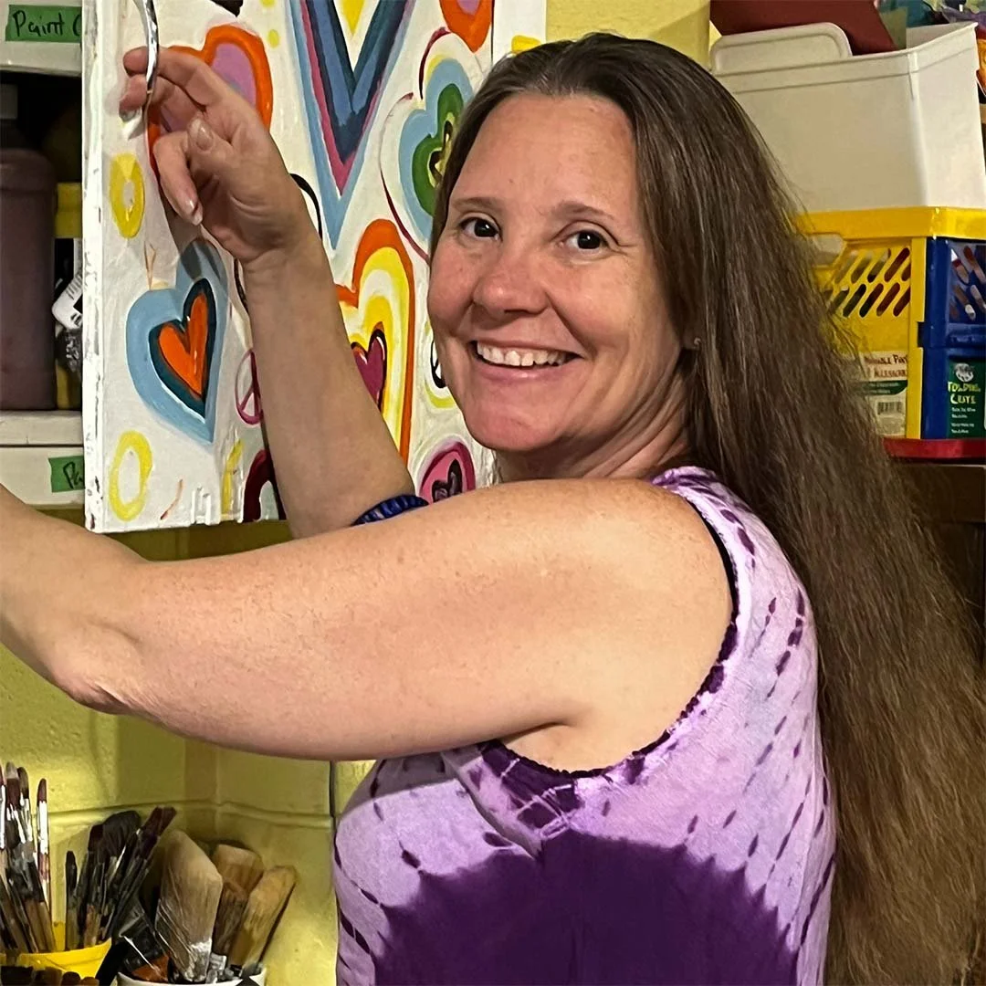 Shelley smiles at the camera as she looks through supplies