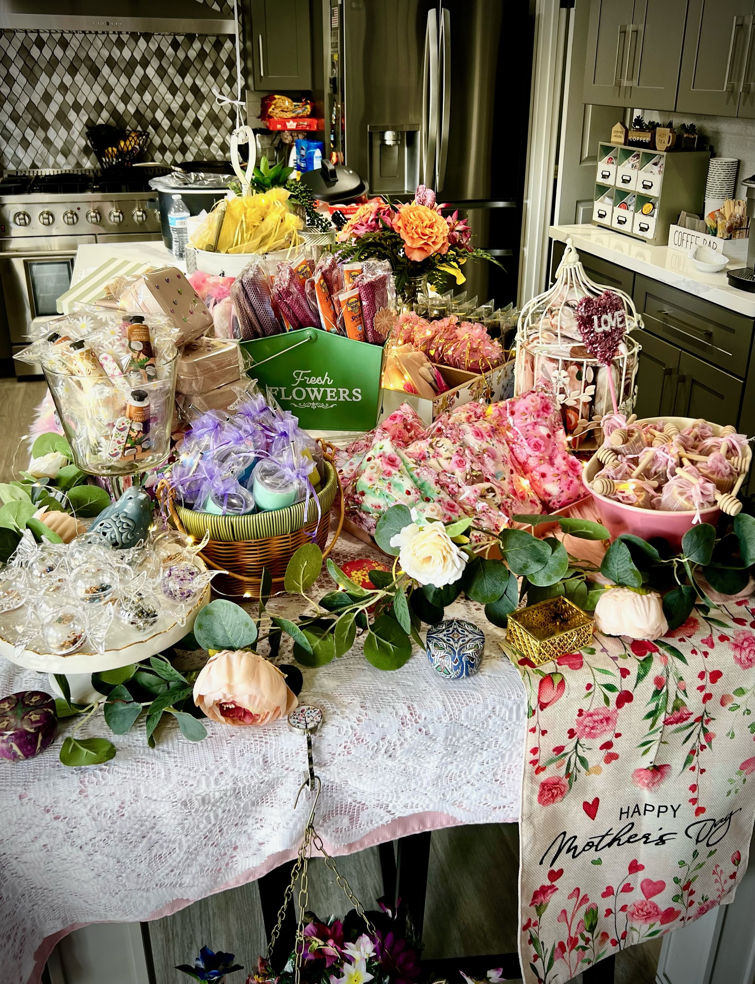 Table set up for Mother's Day celebration with flowers, gifts, and decorations.