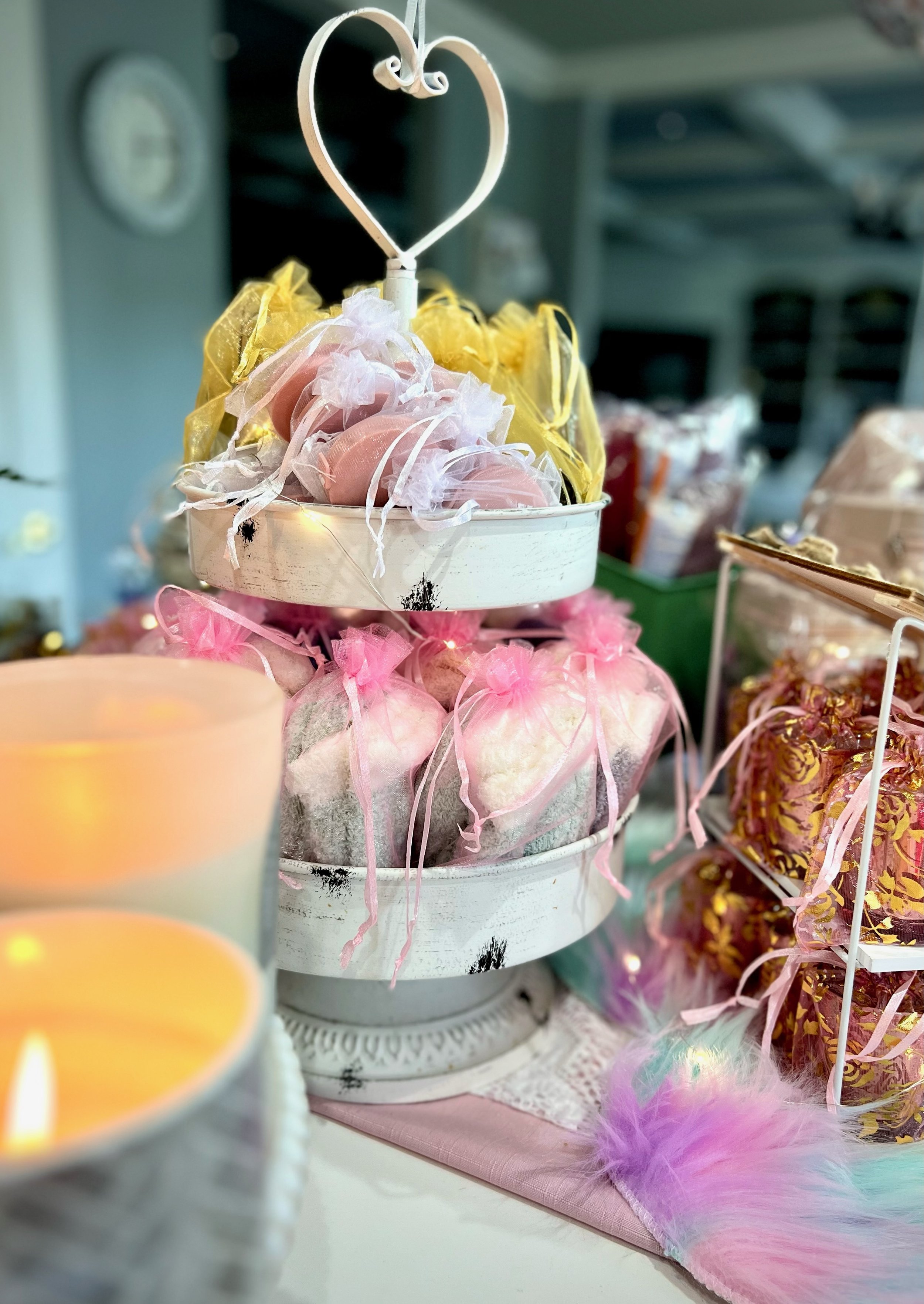 Tiered heart-shaped display with decorative pouches and colorful packaging and candles for a Mother's Day Bunco party,