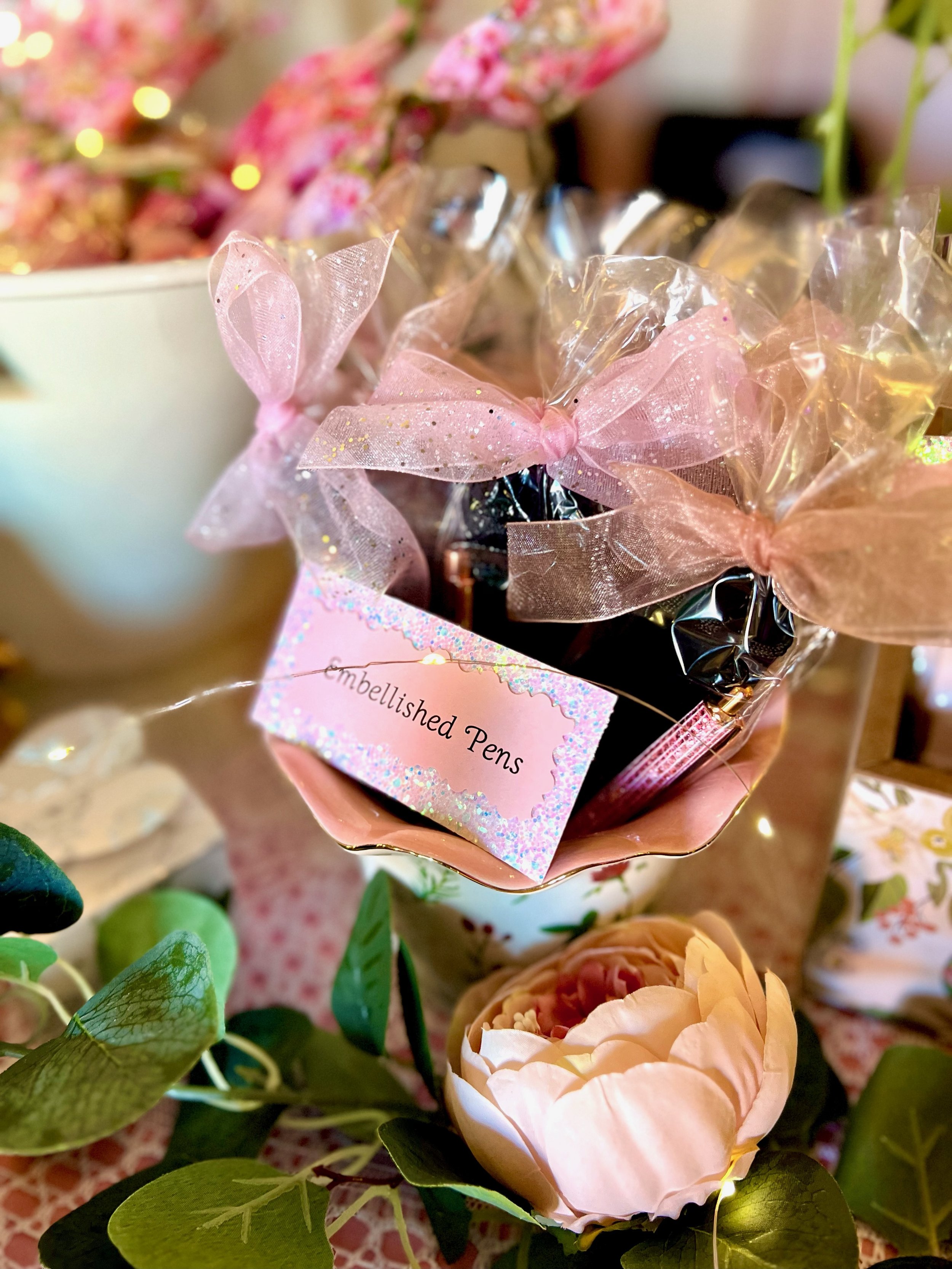 Decorative display with embellished pens wrapped with pink bows.