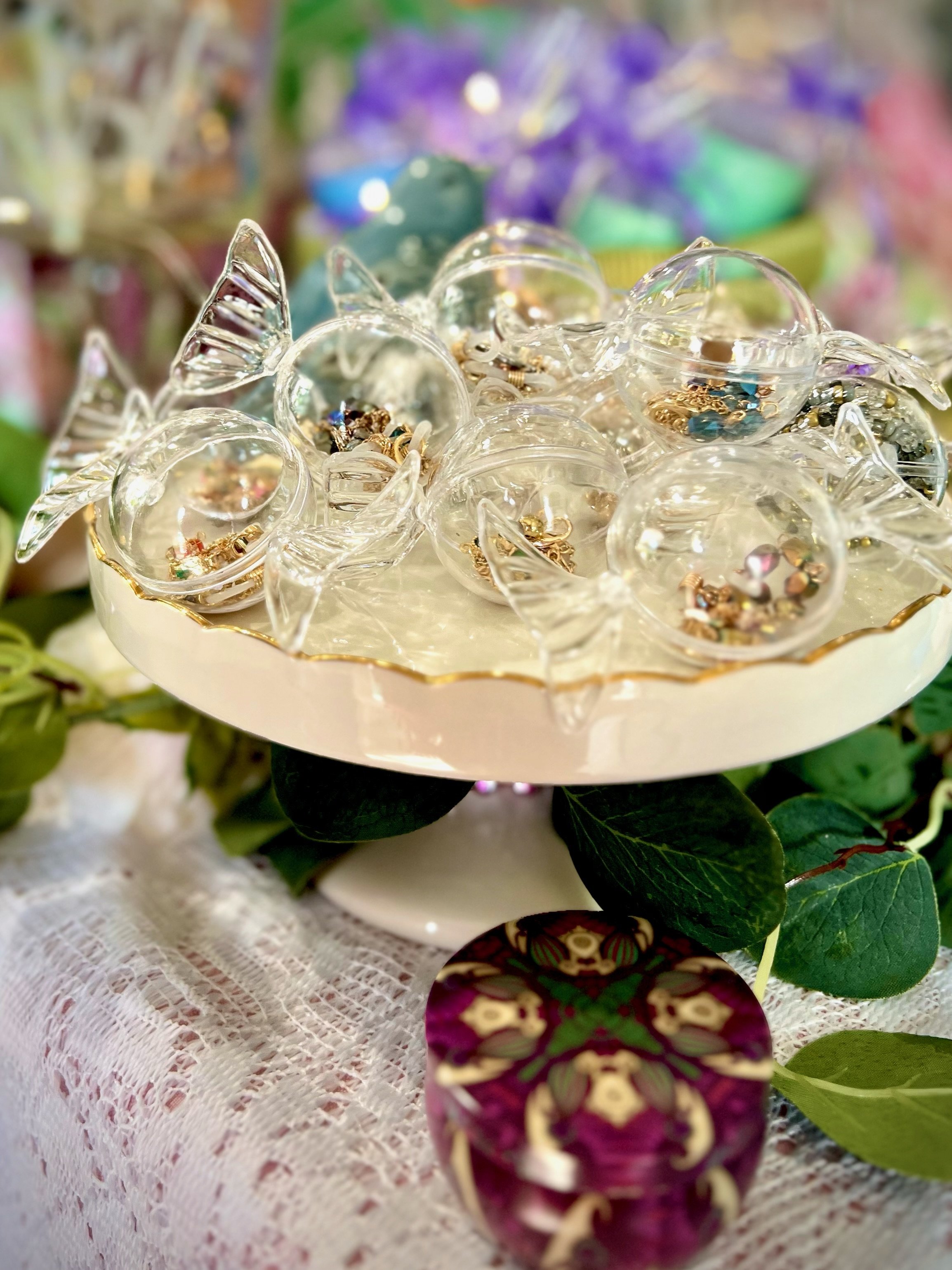 Decorative glass dish with clear glass candy-shaped containers, each holding eye glass chains.