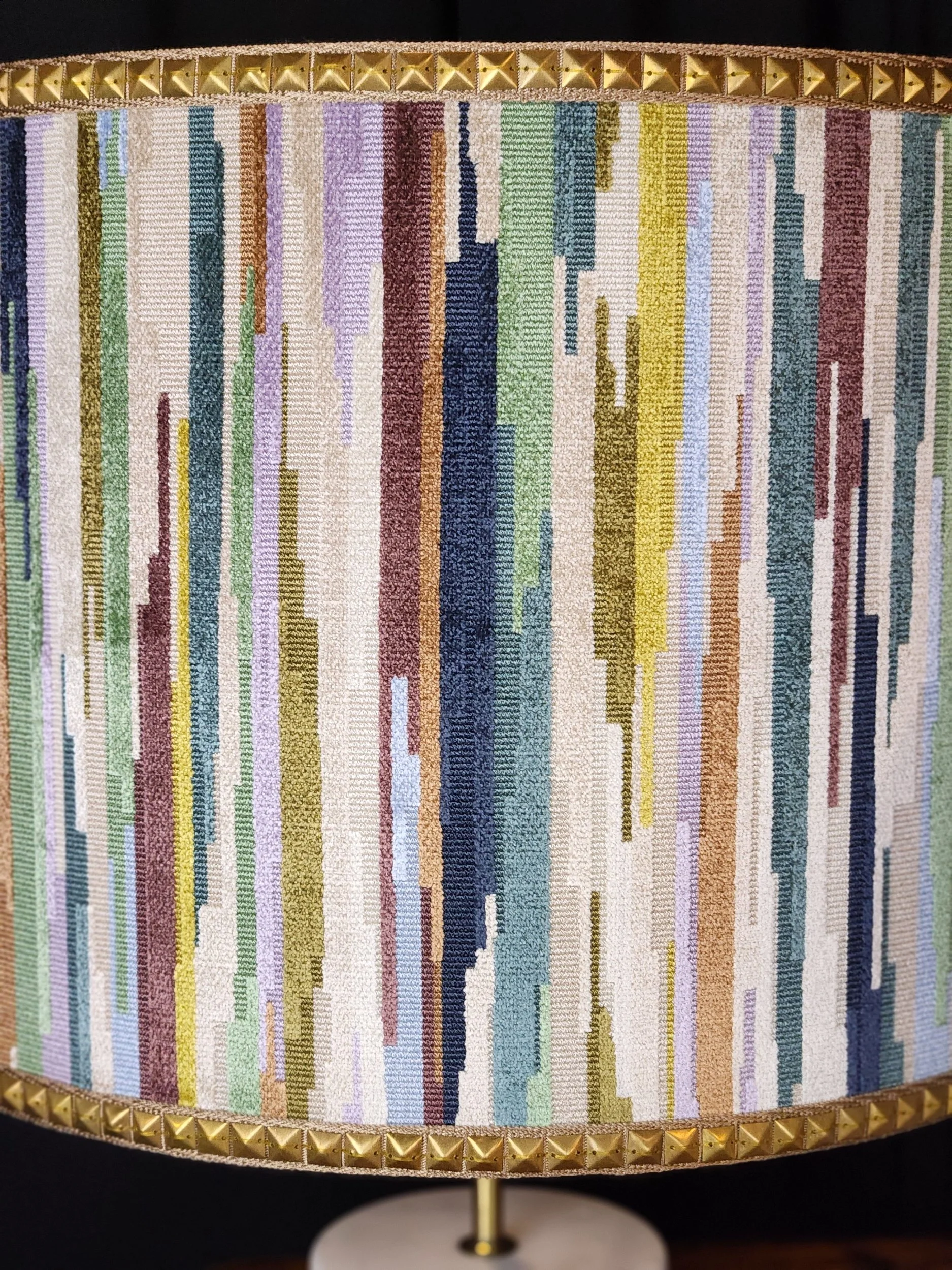 Colorful striped table lamp with gold pyramid studs along the top and bottom edges.