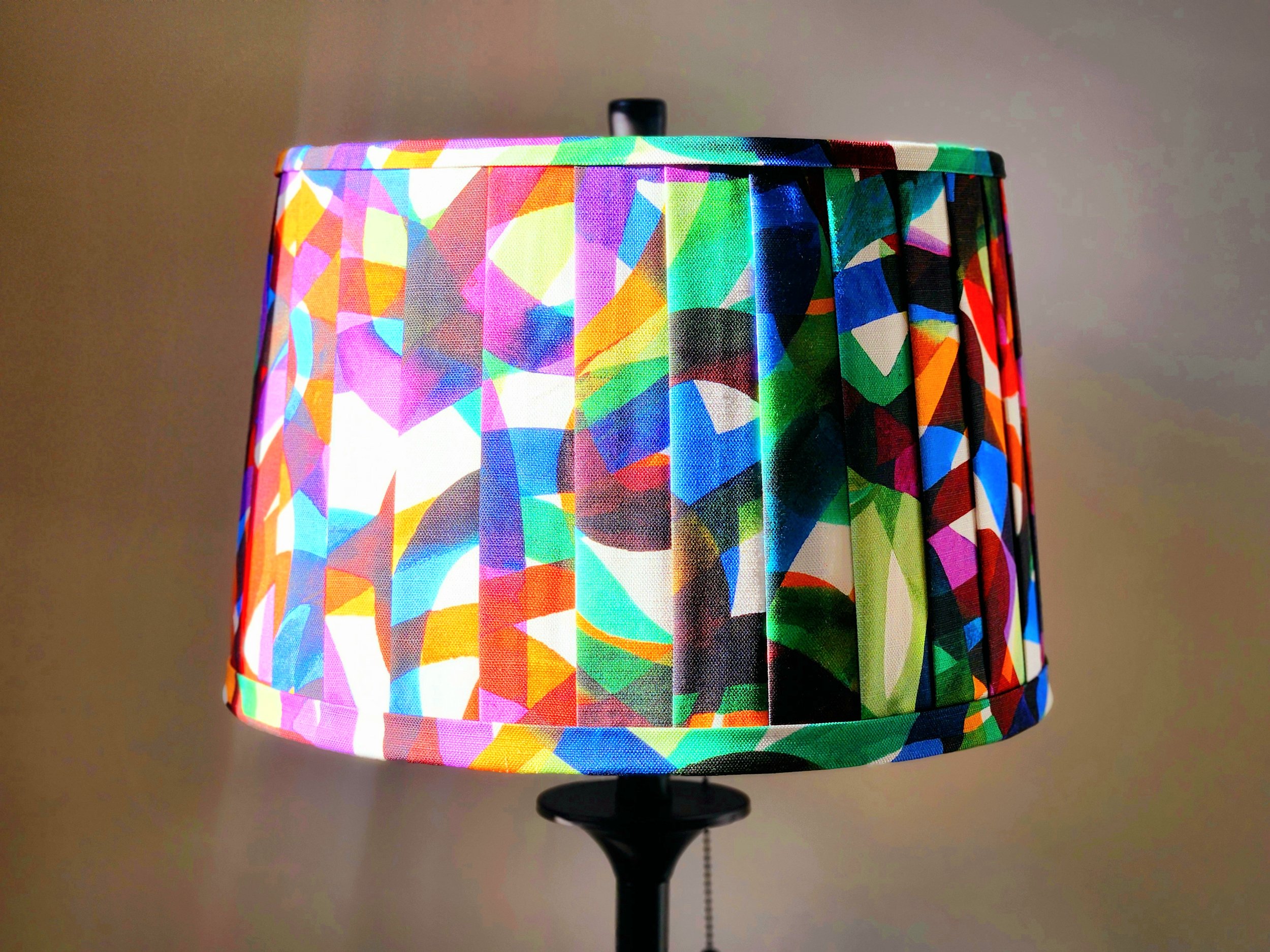 A vibrant lampshade with a colorful abstract pattern. The pleated design adds texture and visual interest to this statement piece.