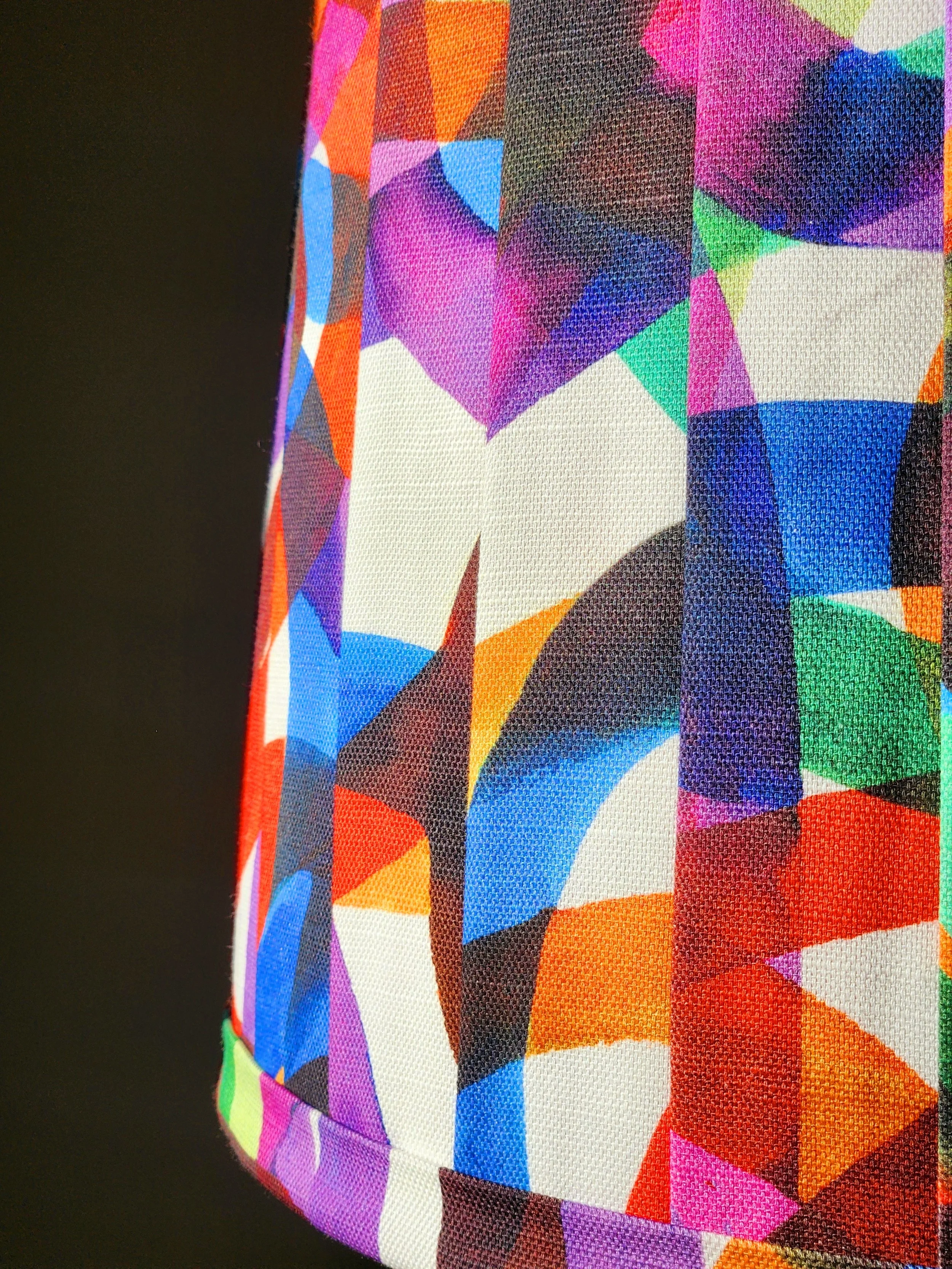 Close-up of a lampshade with a vibrant, abstract pattern in a kaleidoscope of colors. The texture and detail of the fabric are highlighted.