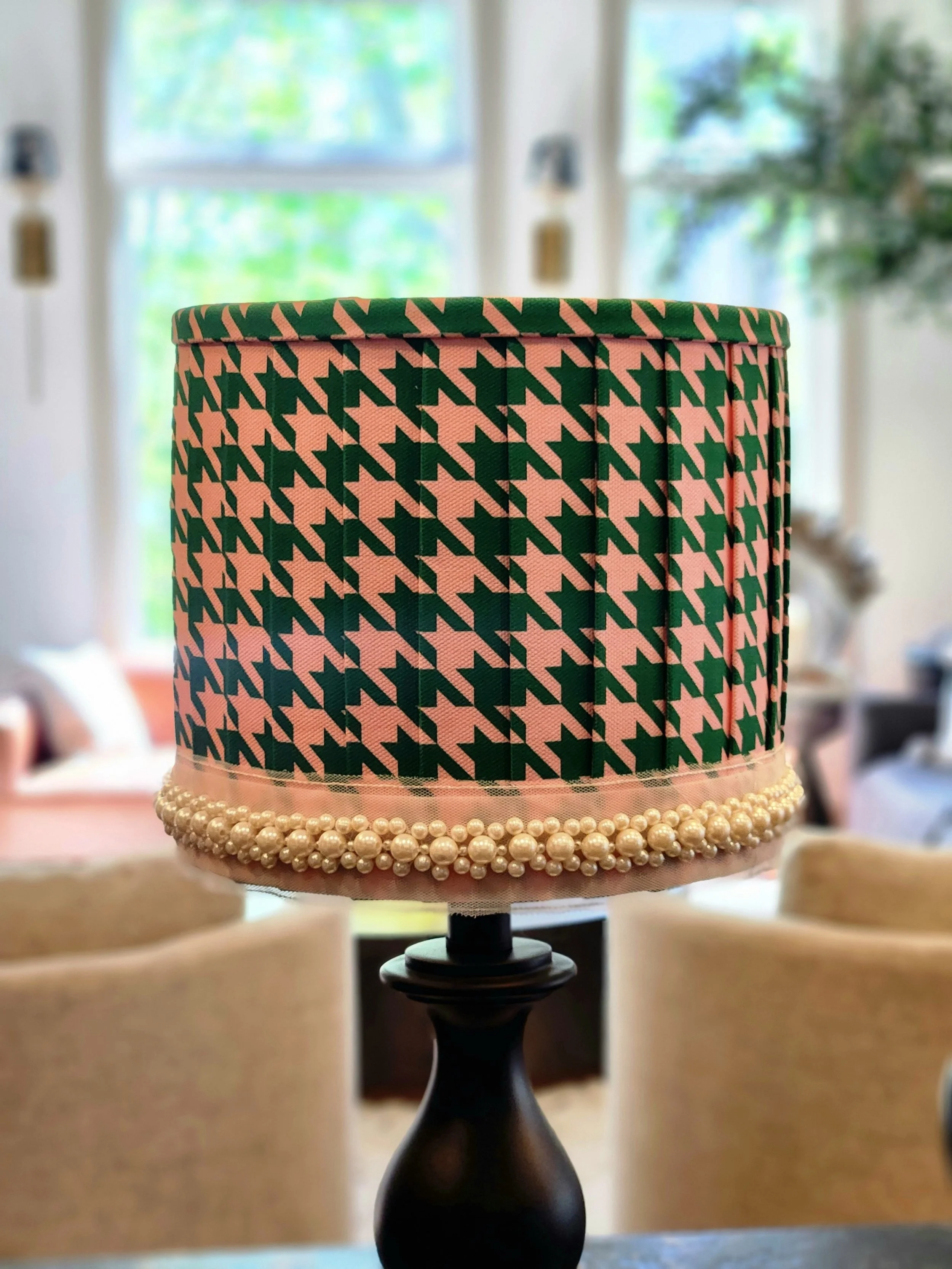 Lamp with houndstooth patterned shade and pearl trim in a living room.