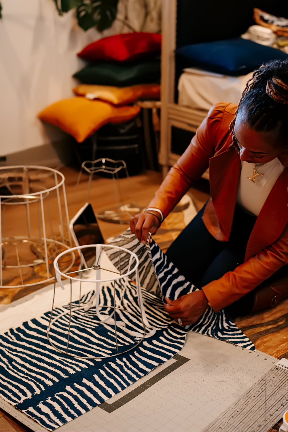 Person crafting with zebra print fabric and wire frame, surrounded by cushions.