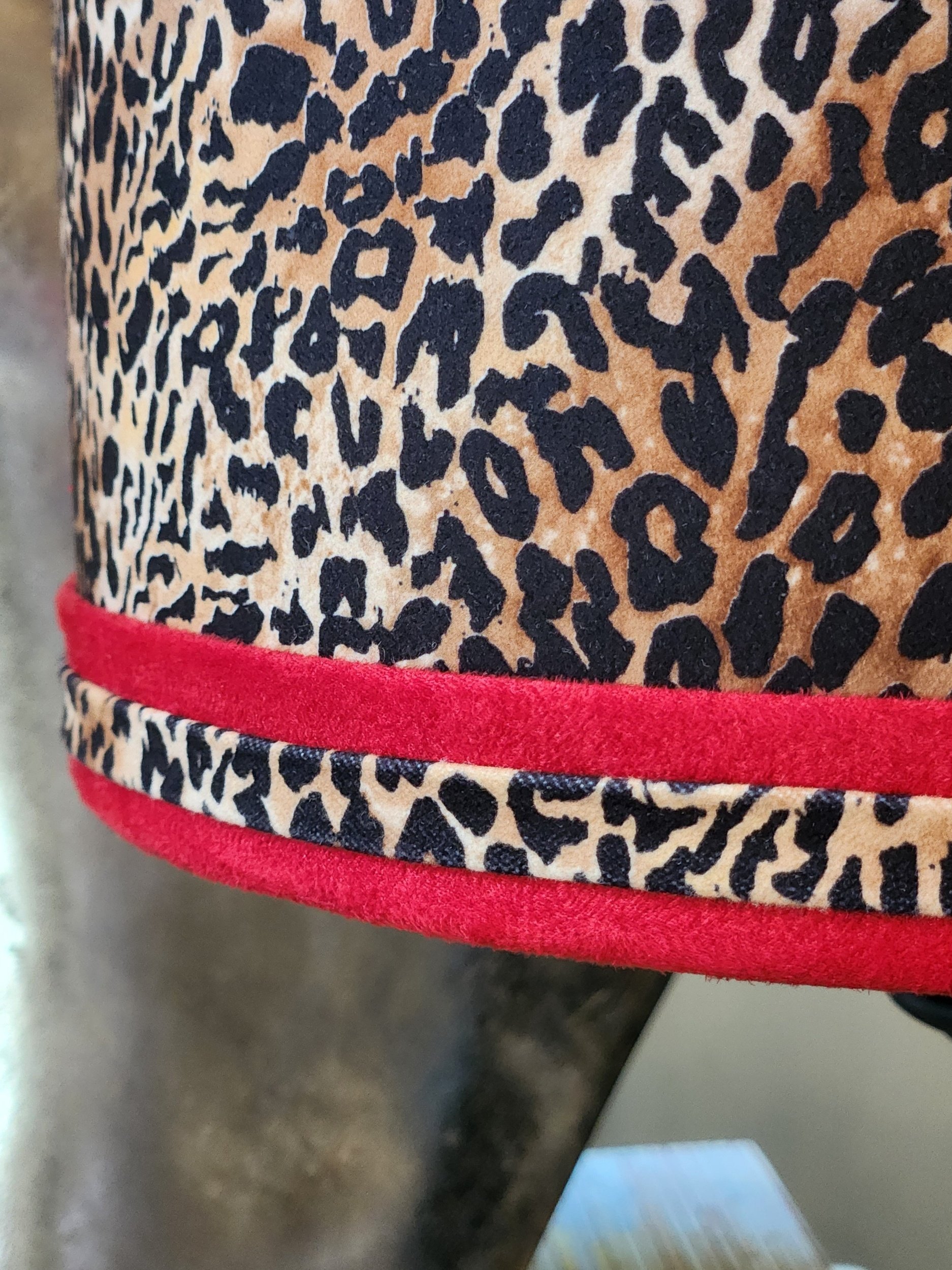 Close-up of a leopard print pattern on a fabric with a red trim at the bottom.