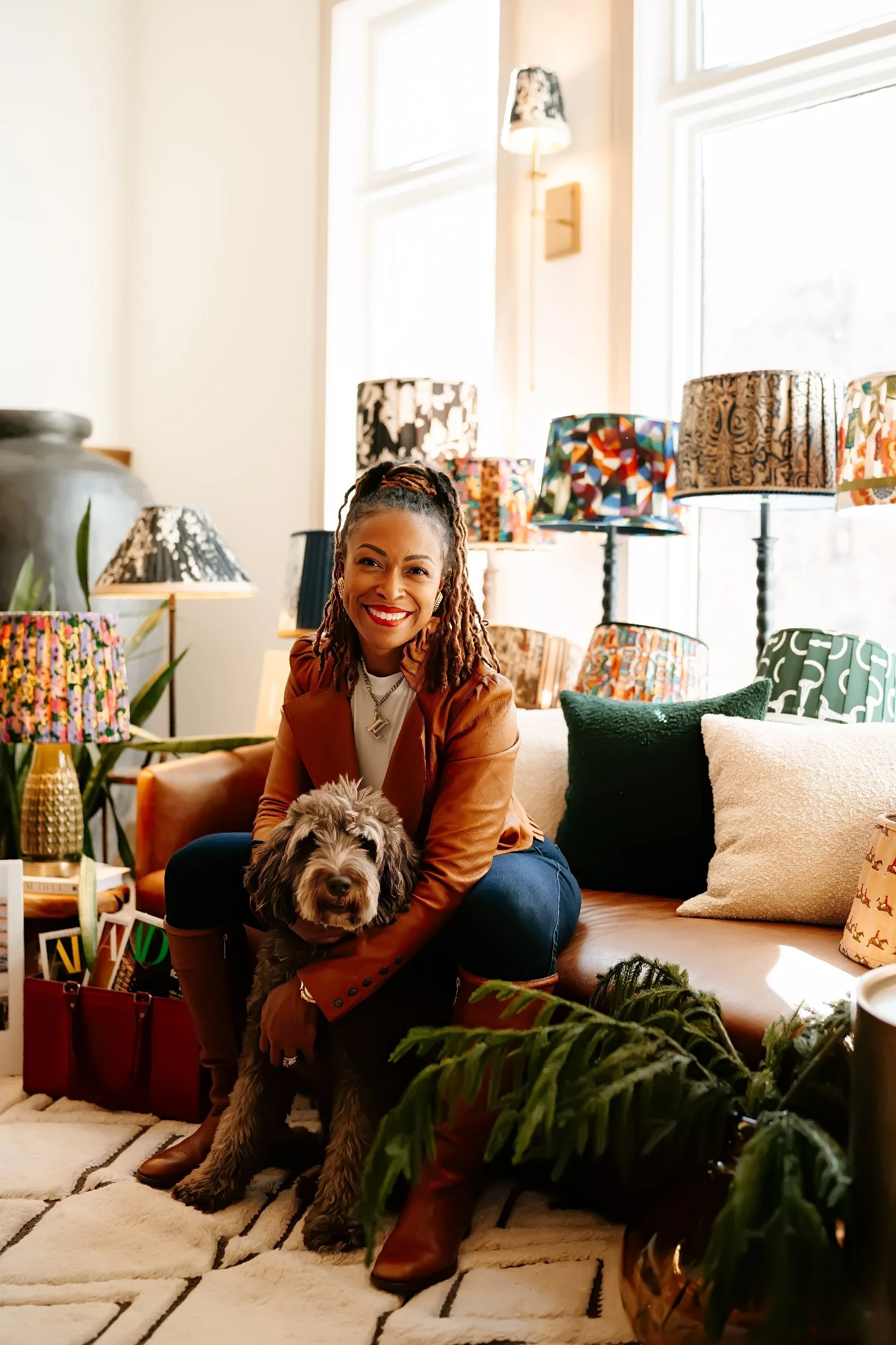 Person sitting on a couch with a dog, surrounded by colorful lampshades and cushions in a cozy living room.