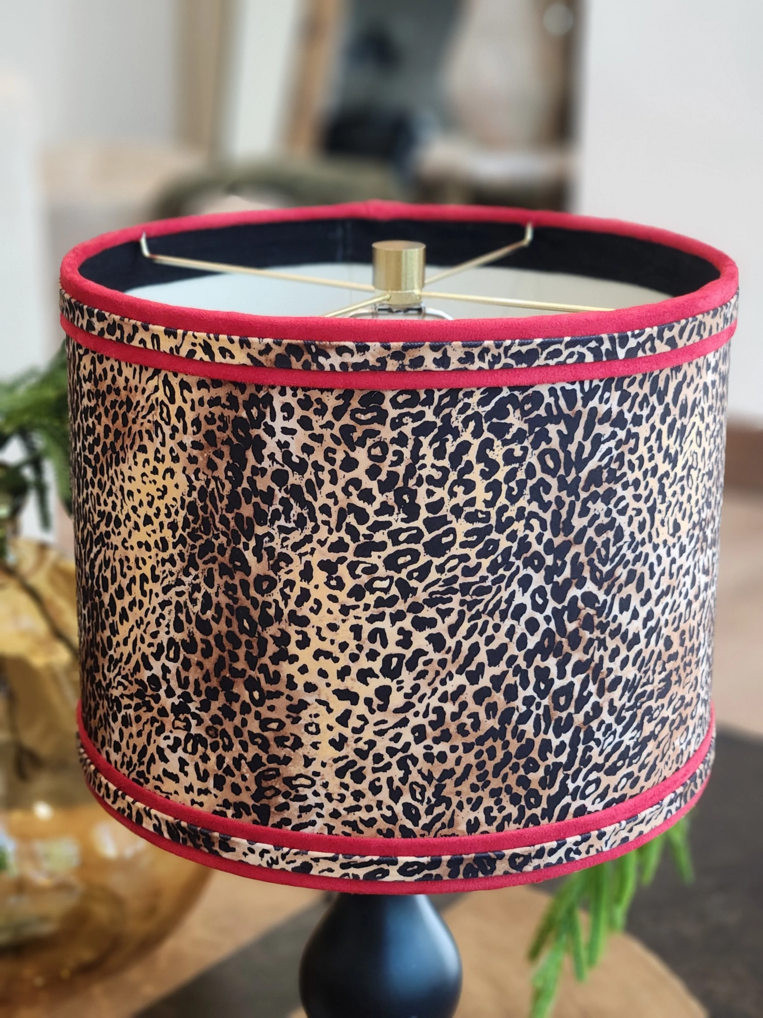 Decorative table lamp with a leopard print fabric shade and a black base, set on a wooden surface.