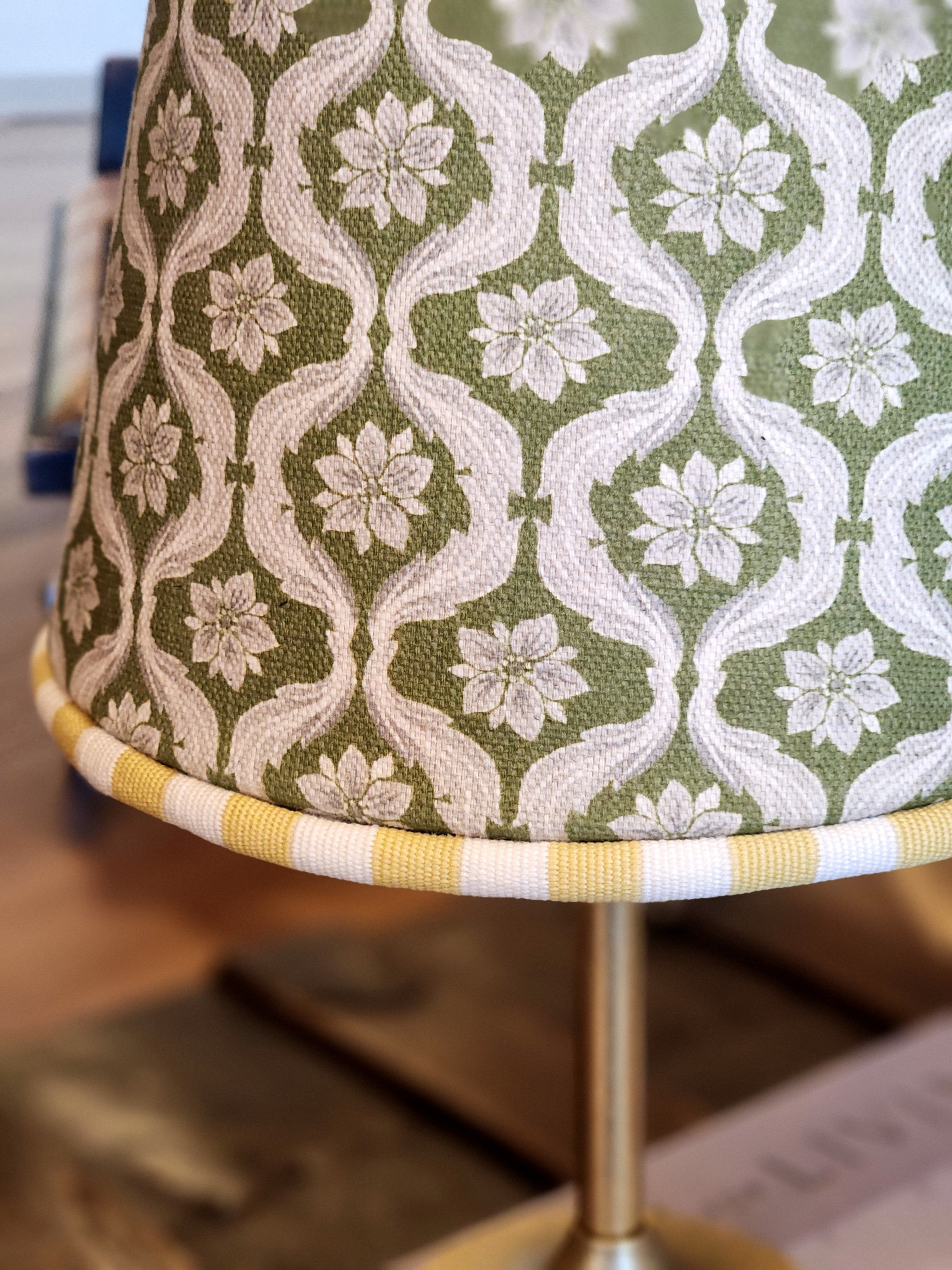 Close-up of a fabric lampshade with a green and white floral and geometric pattern.