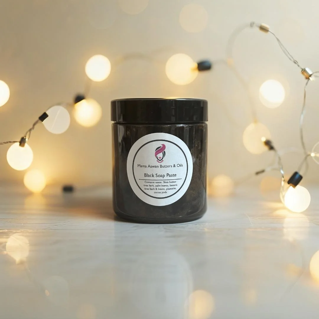 Raw African Black Soap Paste displayed with warm string lights in the background.