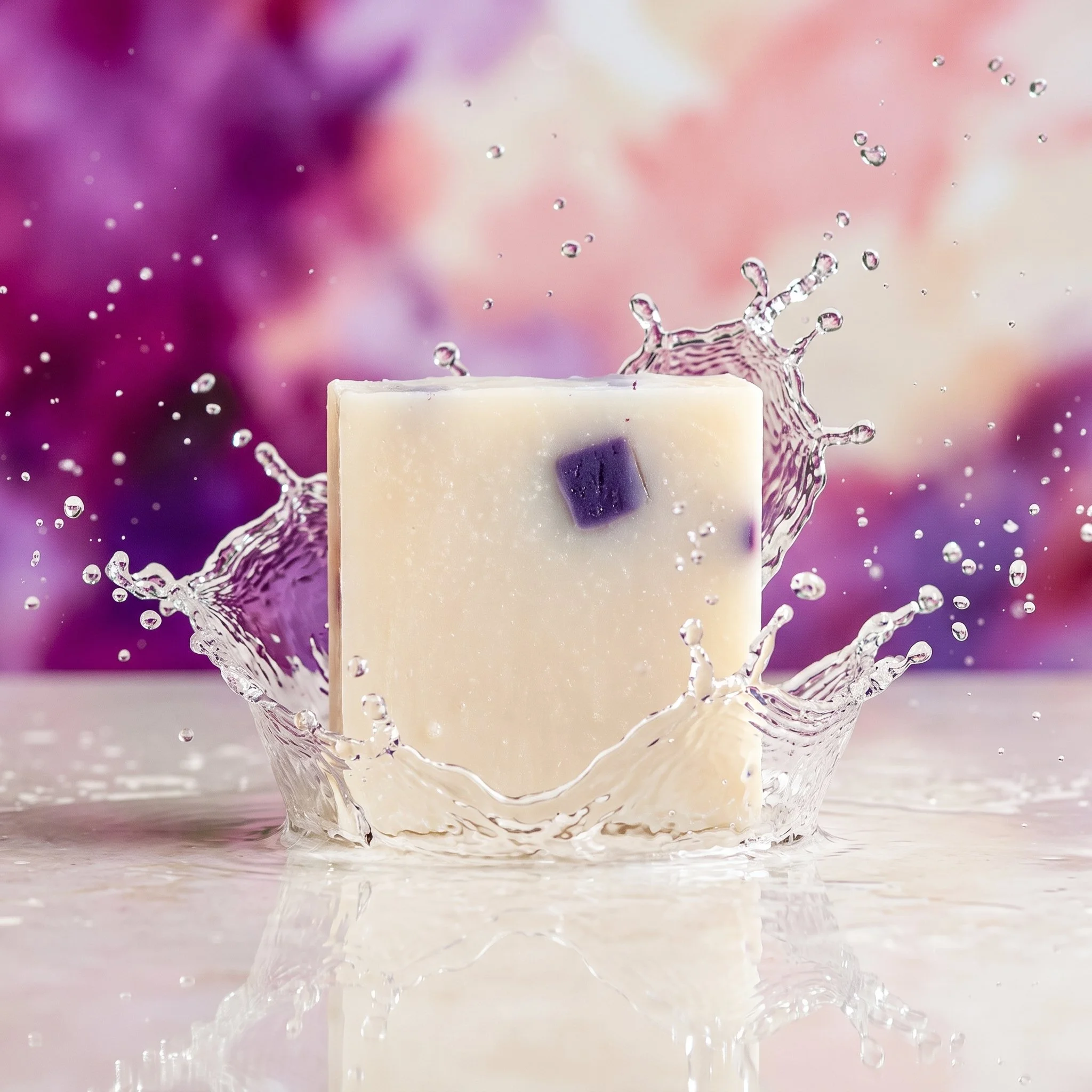 Black Raspberry Vanilla Soap Bar with water splash styling against a pink and purple berry-inspired background.