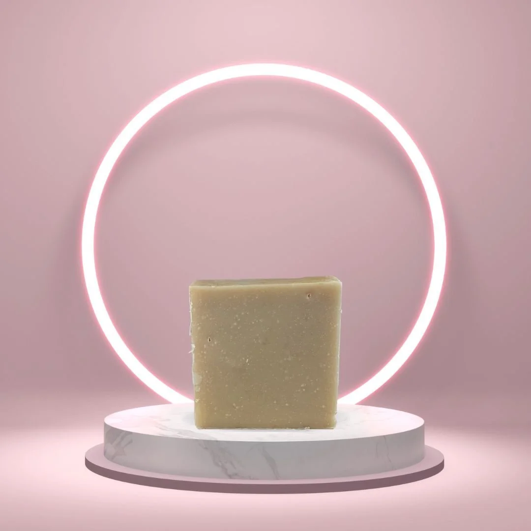 Lemon Coconut Soap Bar on a white pedestal with a glowing pink circle background.