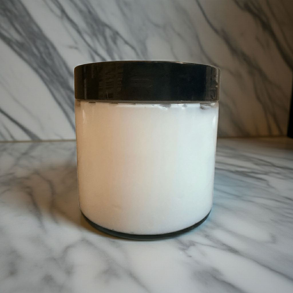 A clean product image of The White Line by Mama Aswan Unscented Raw Sugar Scrub 16oz displayed on gray marble to emphasize its simple, fragrance-free, polished presentation.