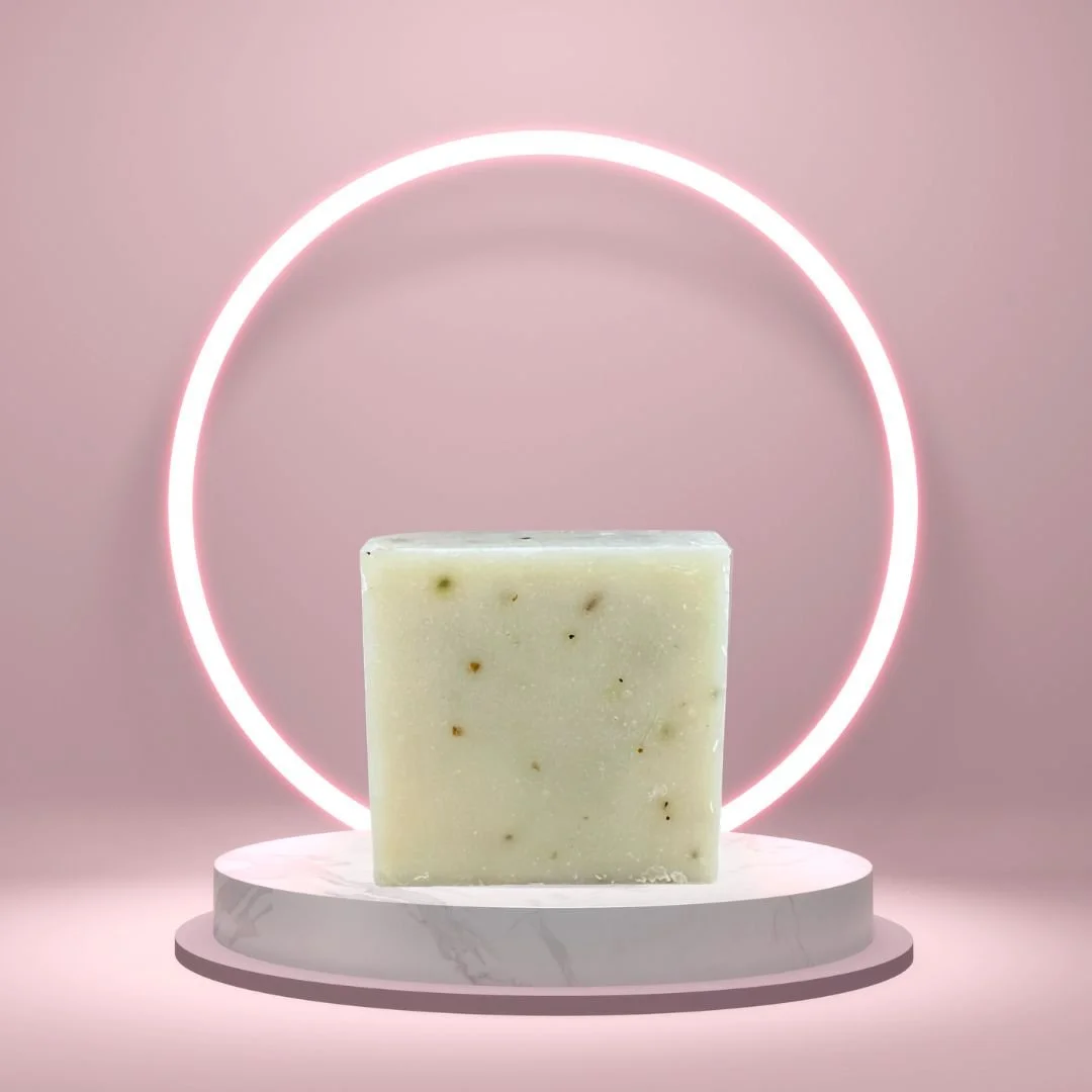 Eucalyptus Lavender Goat’s Milk Soap Bar on a white pedestal with a glowing pink circle background.
