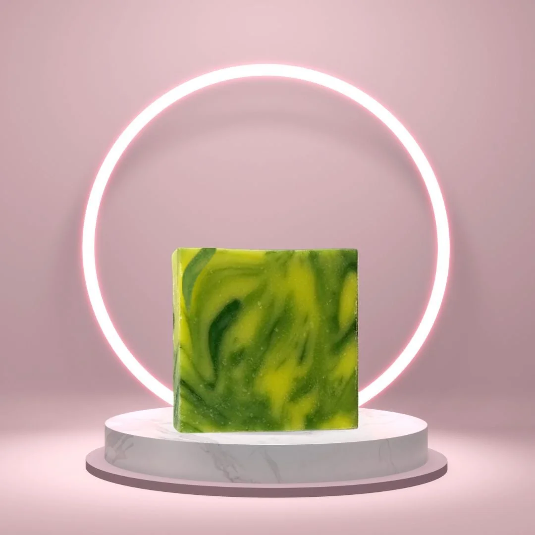 Green and yellow swirled Free Spirit soap displayed on a white pedestal in front of a glowing ring.