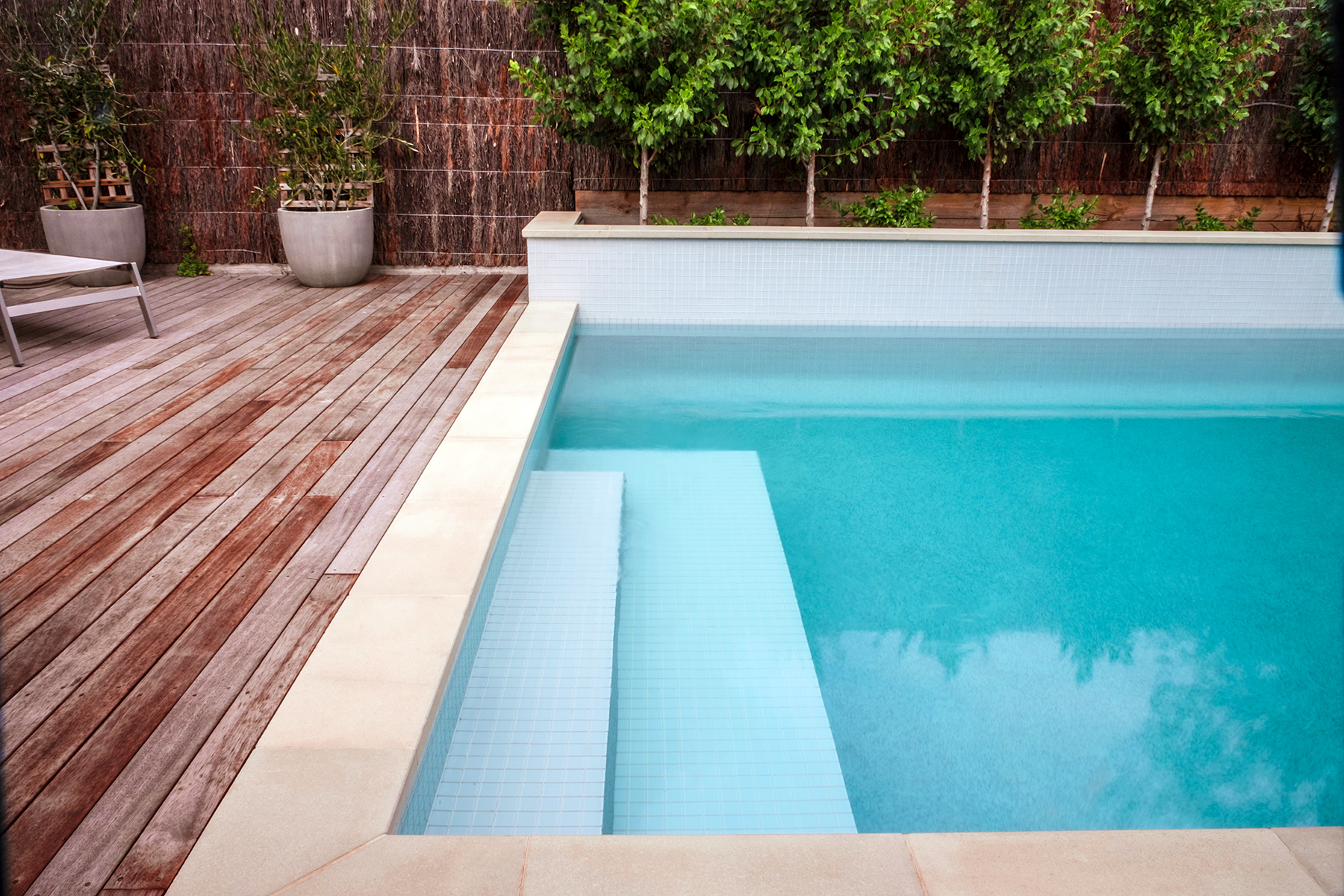 Close up view of the stairs of a luxurious in-ground concrete pool in Mount Martha (Mt Martha) on the Mornington Peninsula with blue water and a fantastic decking area and Pavilion.