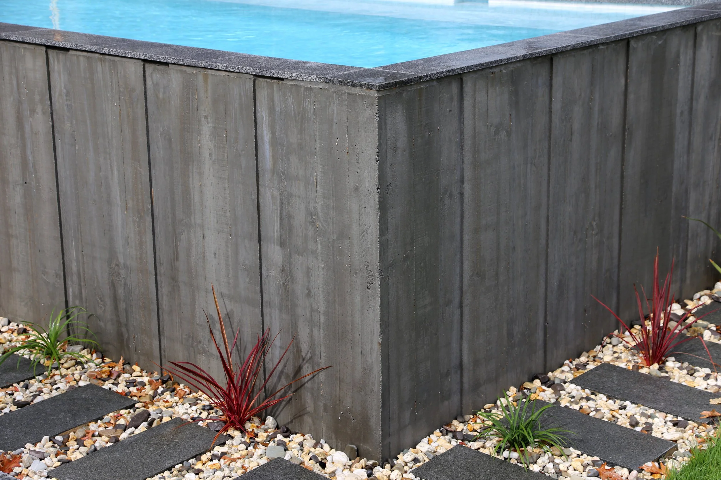 Corner view of a luxurious rustic above ground pool in Mount Eliza (Mt Eliza) on the Mornington Peninsula with blue water and wooden decking surrounding it.