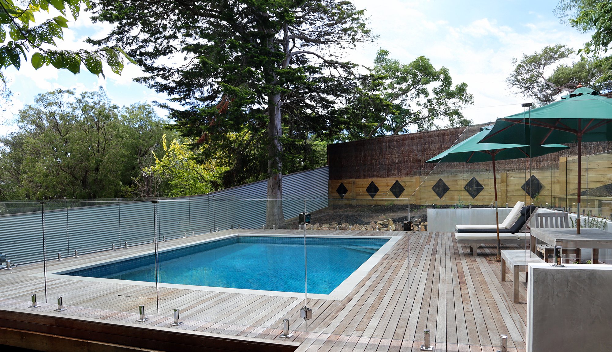 Side view of a swimming pool on Melbourne's Mornington Peninsula with blue water and a decking sitting area.