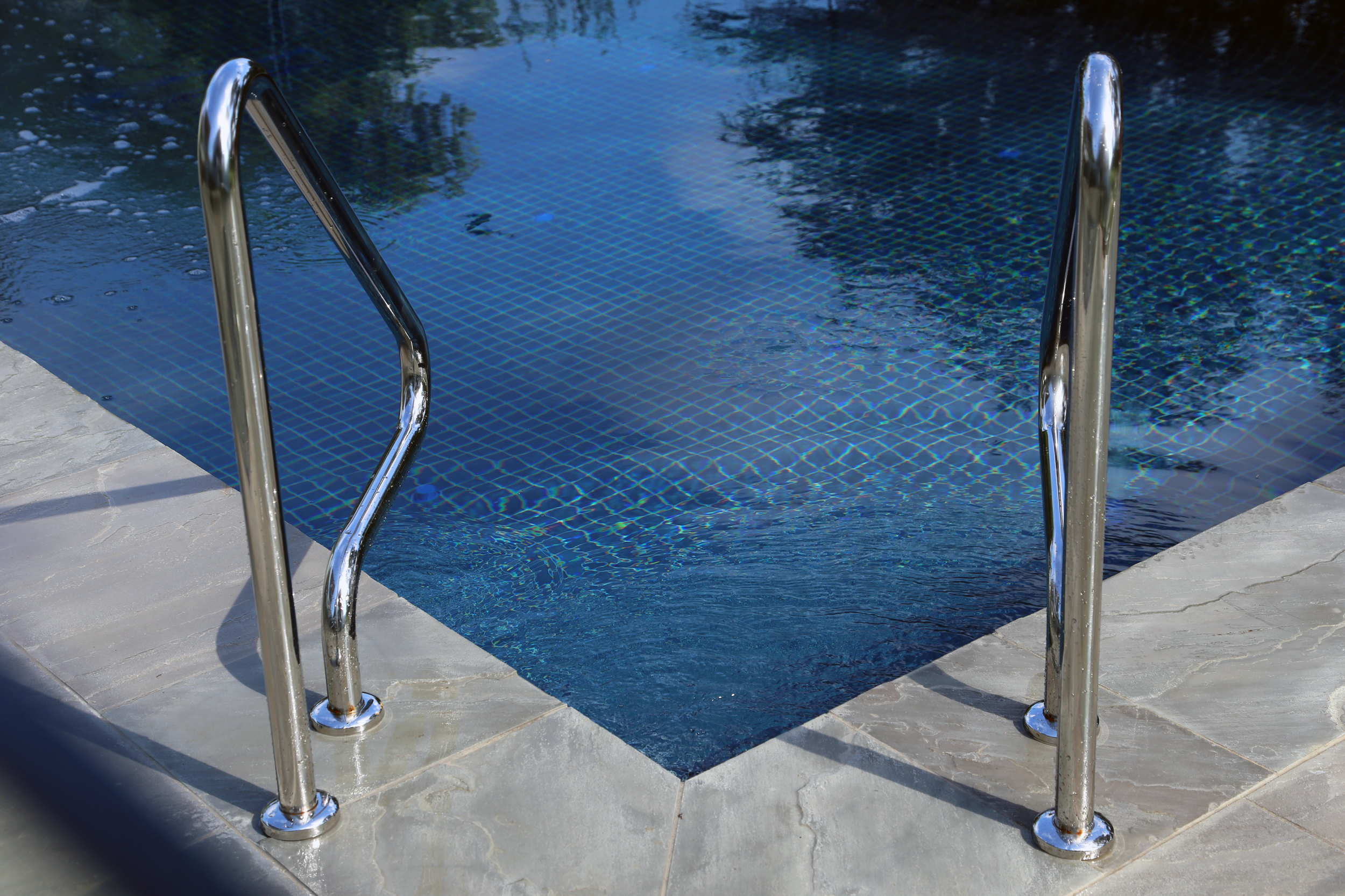 Close up of a luxurious beach side in-ground pool in Mount Eliza (Mt Eliza) on the Mornington Peninsula with blue water and a barbecue sitting area.