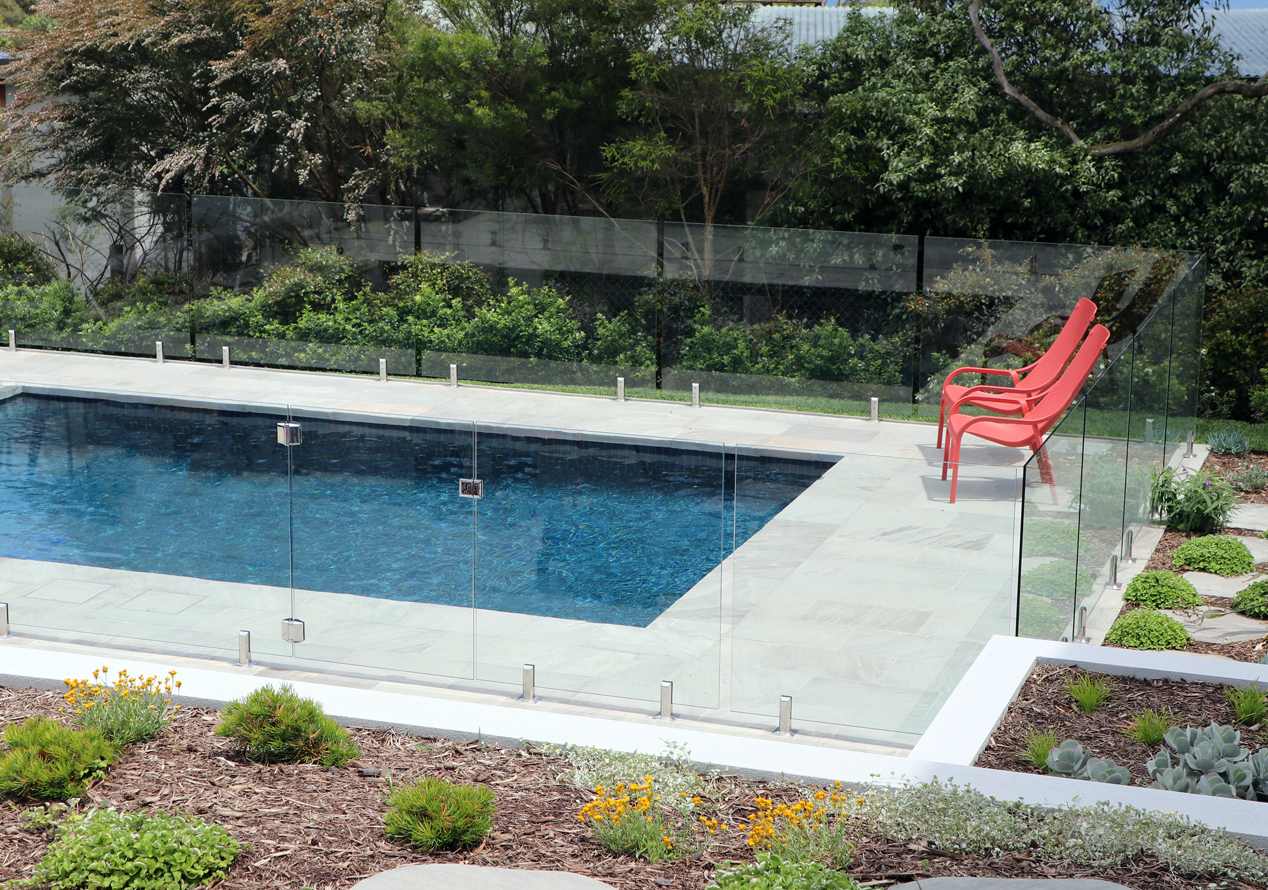Closer side view of a luxurious beach side in-ground pool in Mount Eliza (Mt Eliza) on the Mornington Peninsula with blue water and a barbecue sitting area.