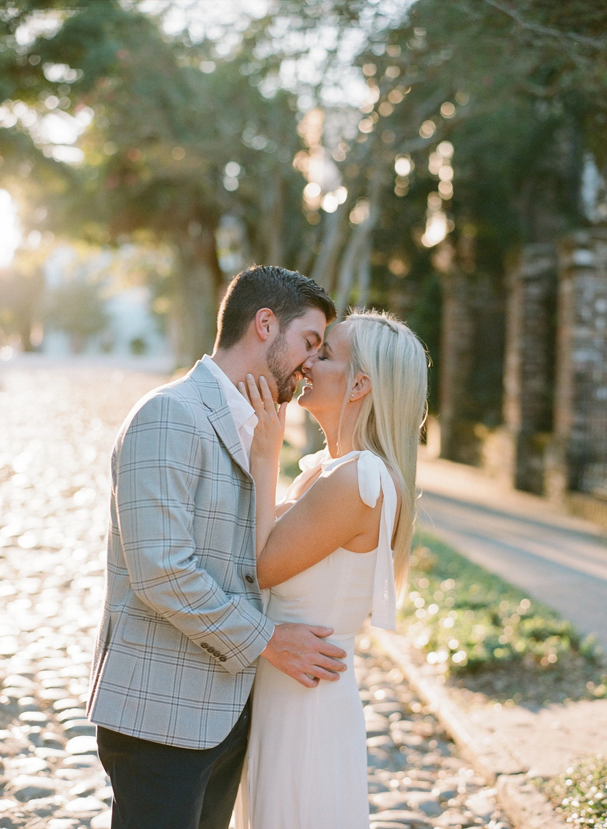 newly engaged couple standing on a cobblestone street during their engagement session in downtown charleston, sc