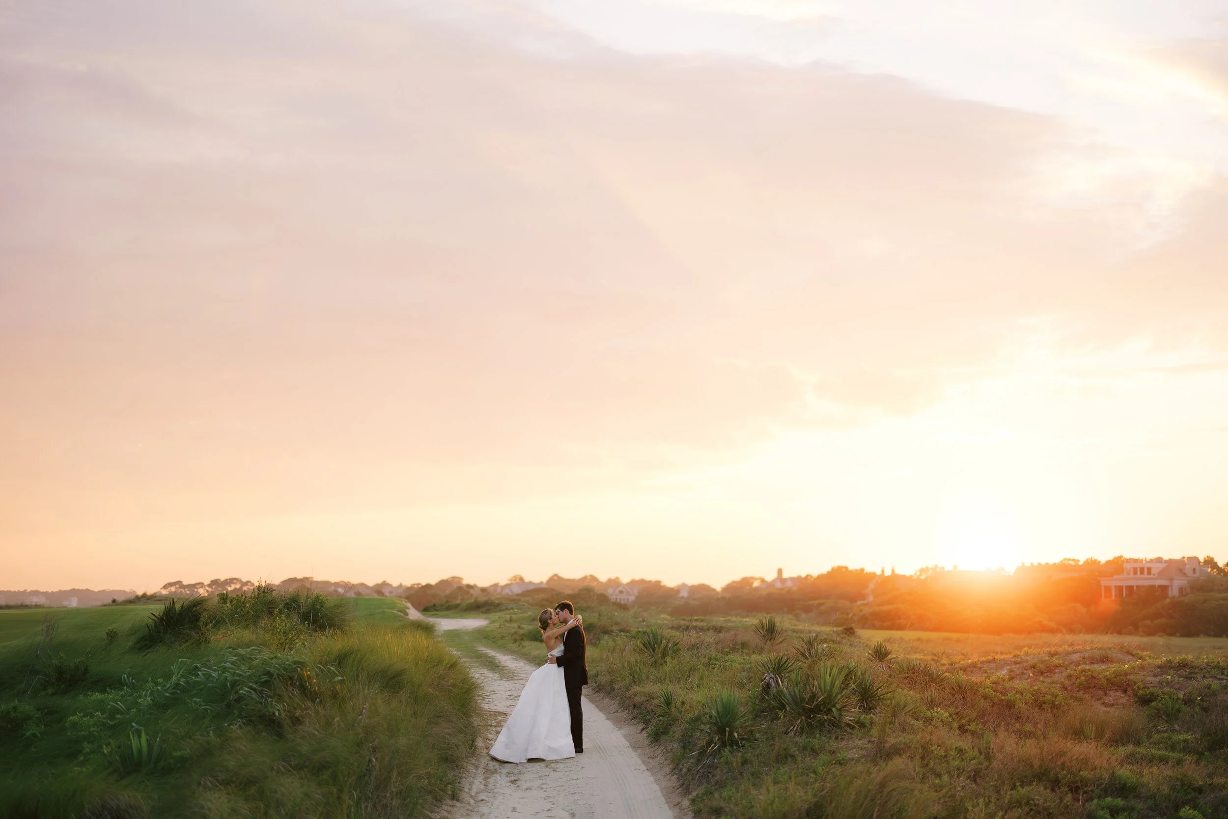 Bride and groom embracing at sunset on a sandy path at the Ocean Course on Kiawah Island