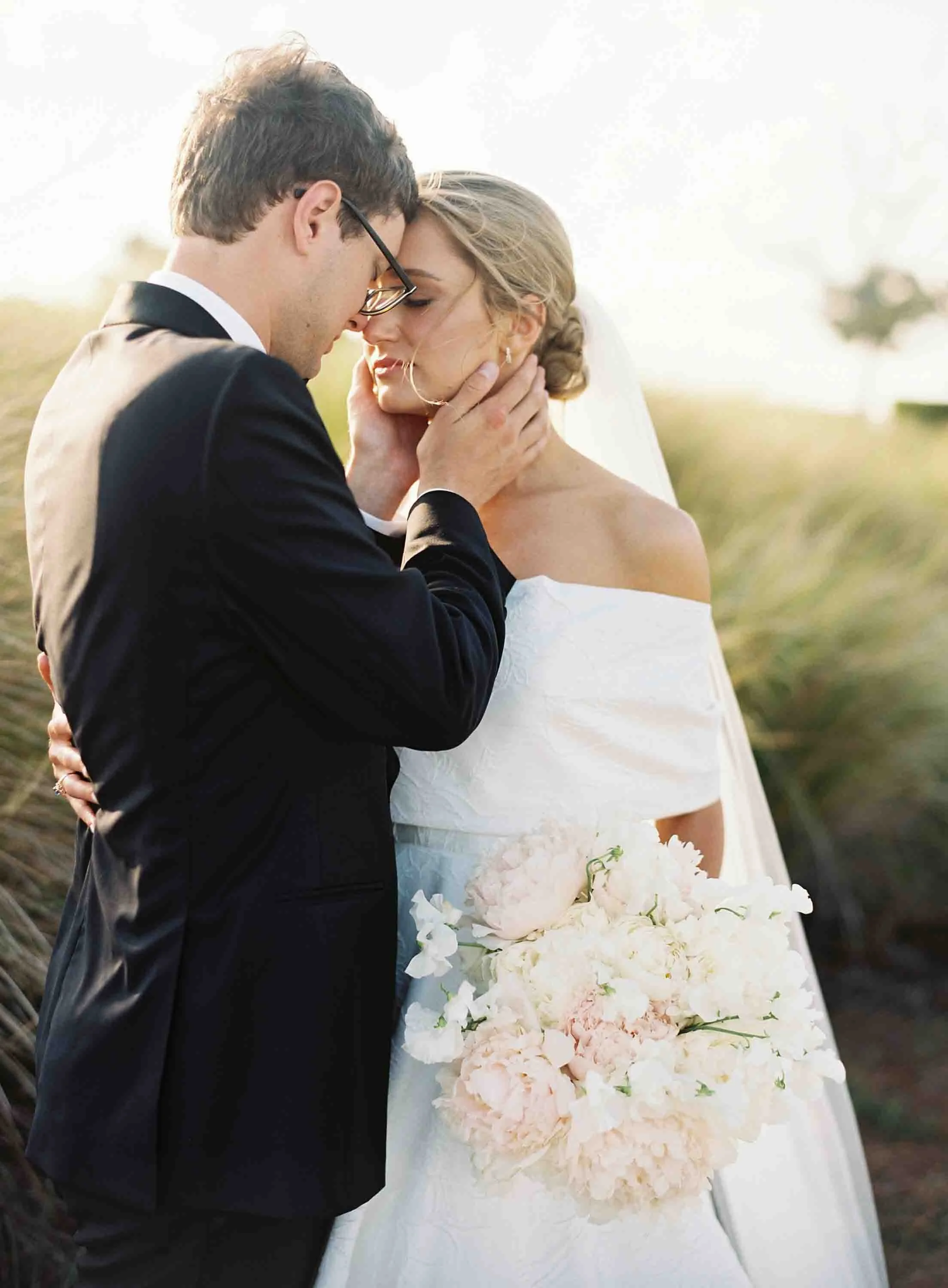Bride and groom sharing a quiet moment together holding a bouquet during golden hour at Kiawah Island