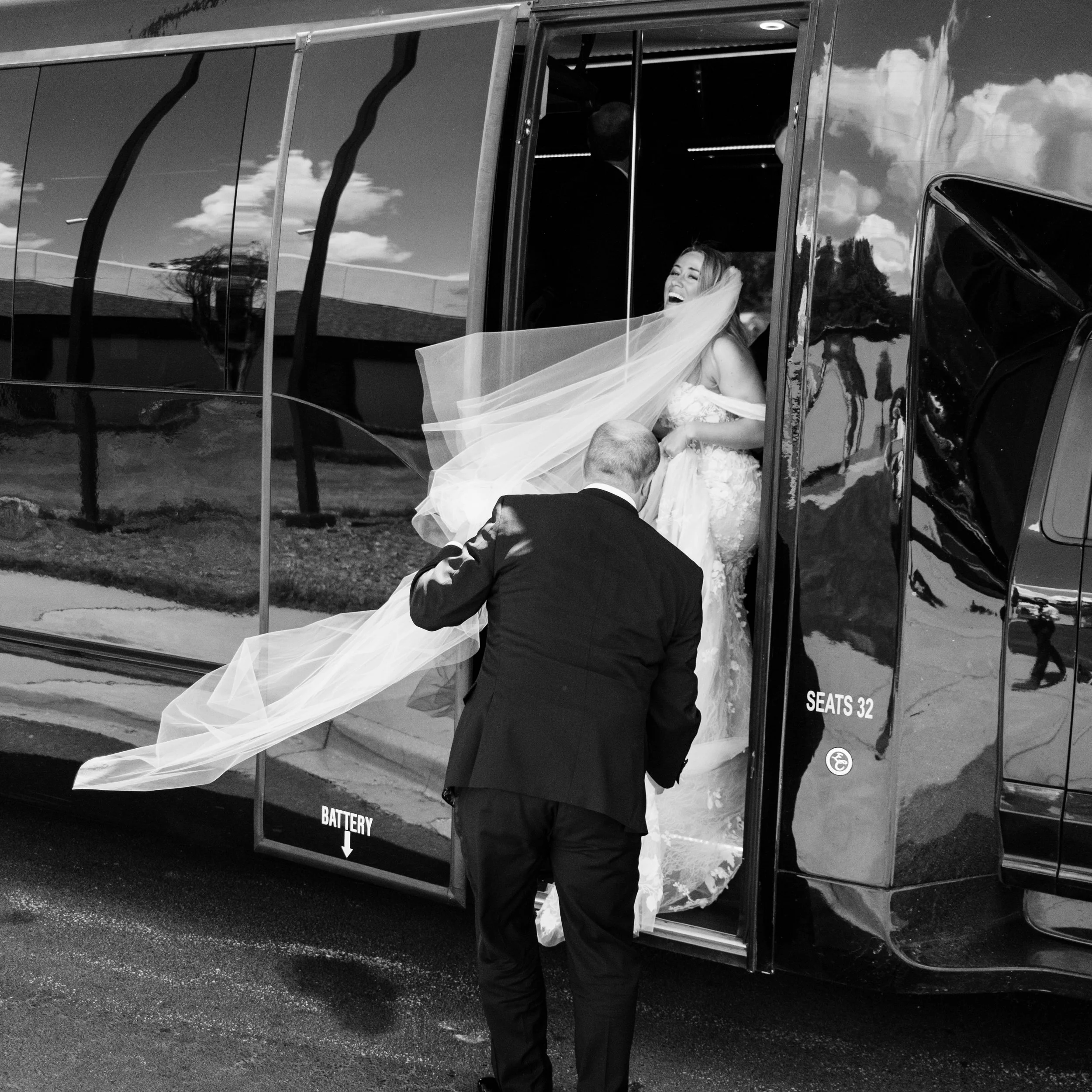 Bride laughing as she steps off shuttle with groom at Hotel Domestique wedding in Travelers Rest South Carolina, veil caught in the wind