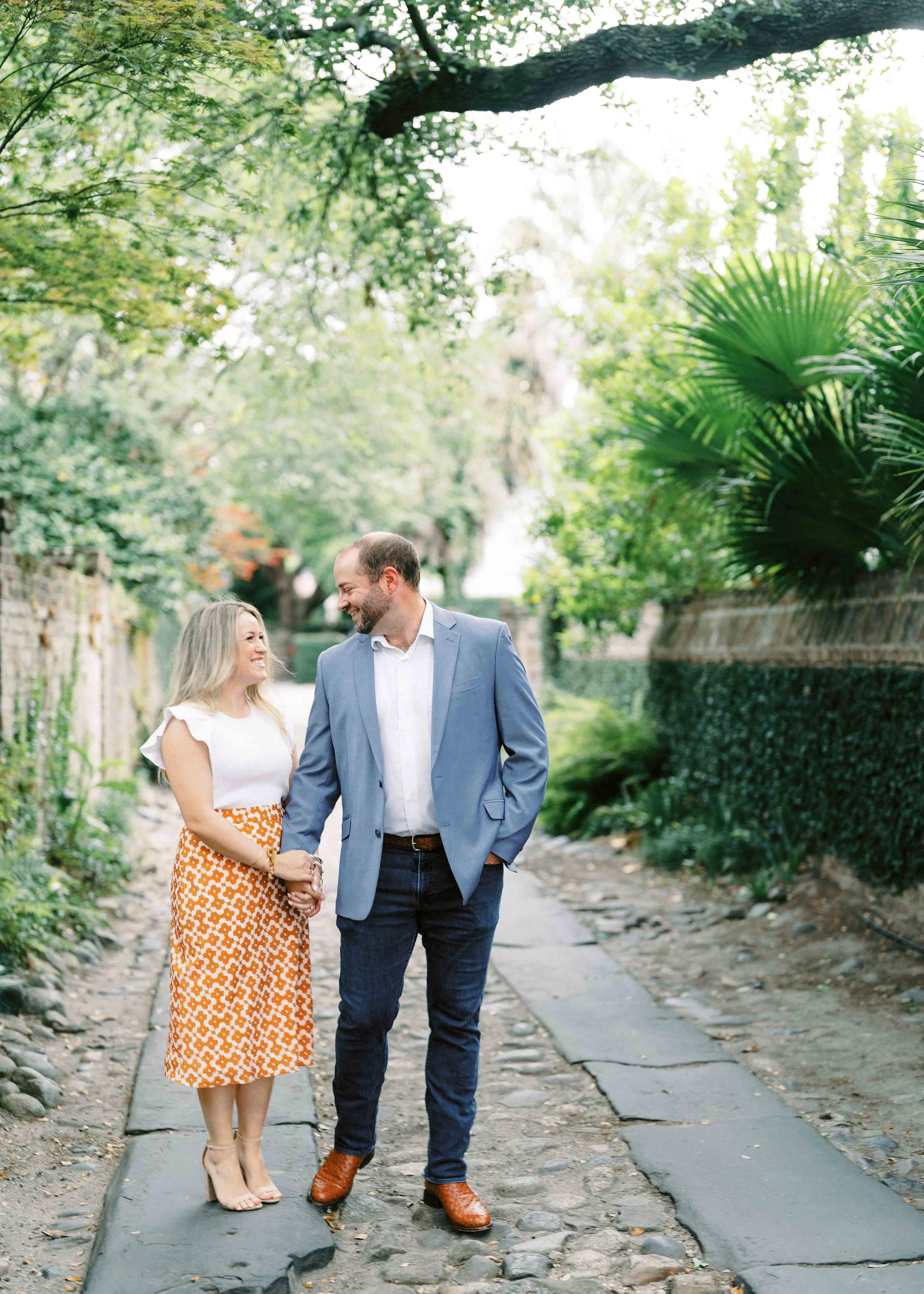 engagement photos on Longitude Lane Charleston with cobblestone path and greenery
