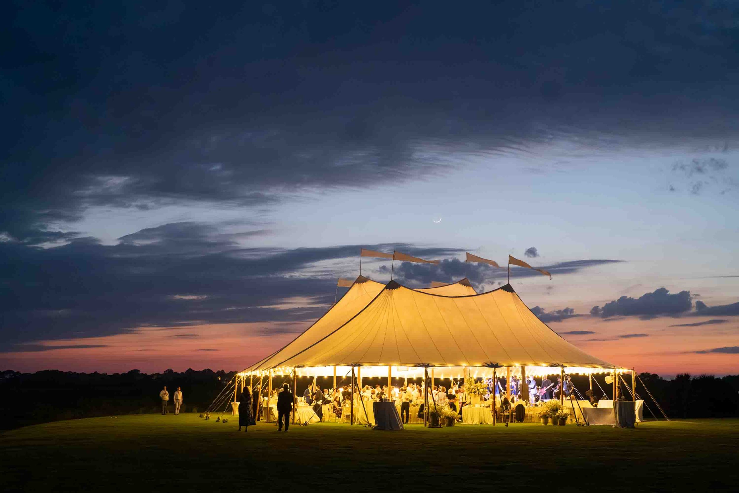 Wedding reception tent glowing at night on the Ocean Course at Kiawah Island