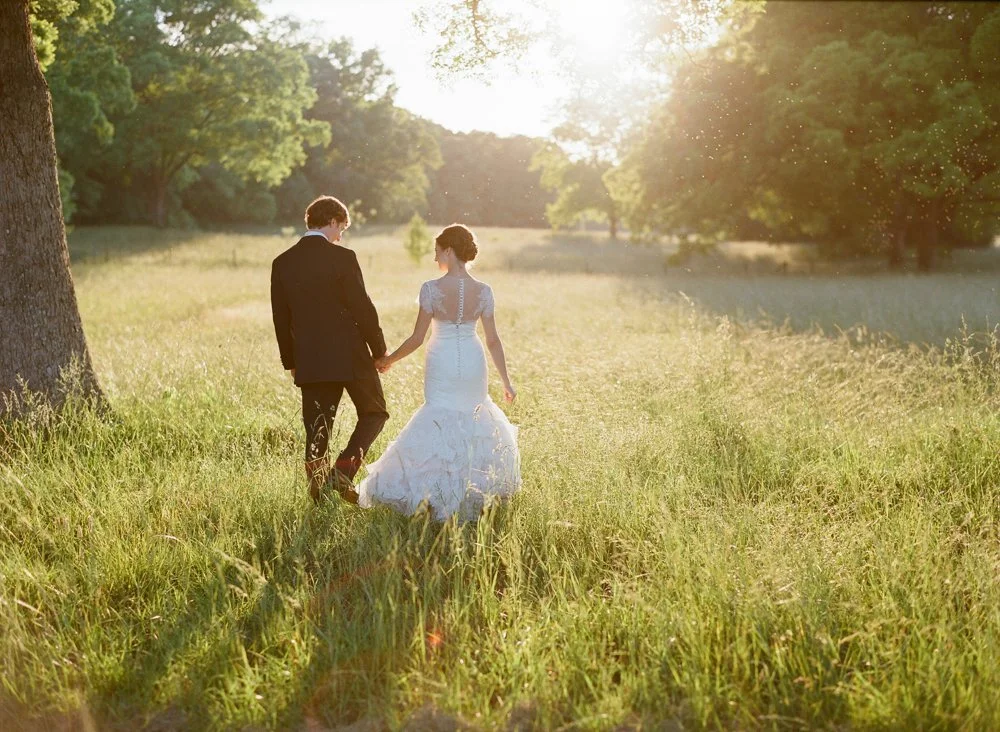Bride and groom walking through field at golden hour during wedding in Georgia countryside