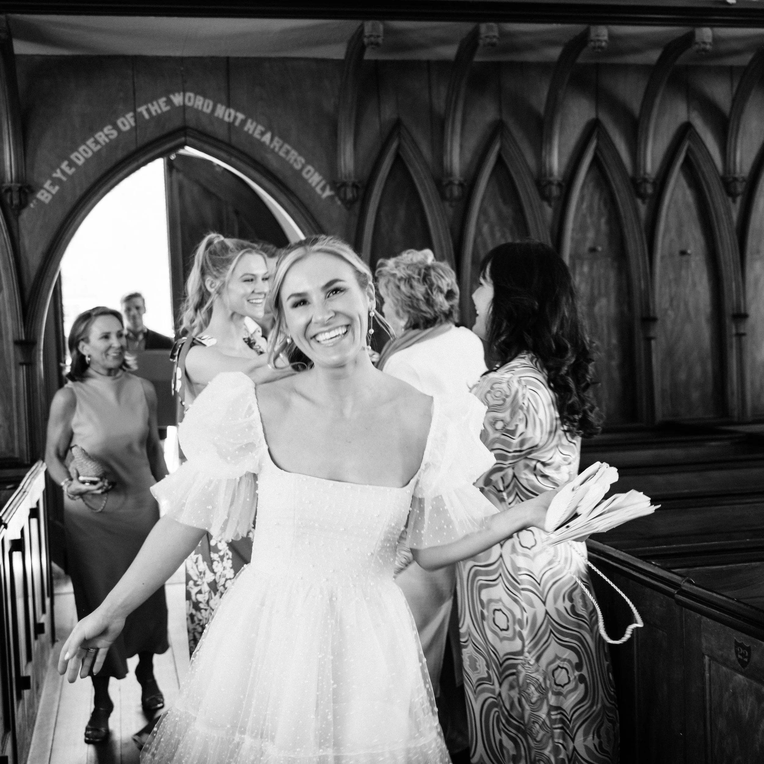 Bride smiling at rehearsal inside historic French Huguenot church before ceremony