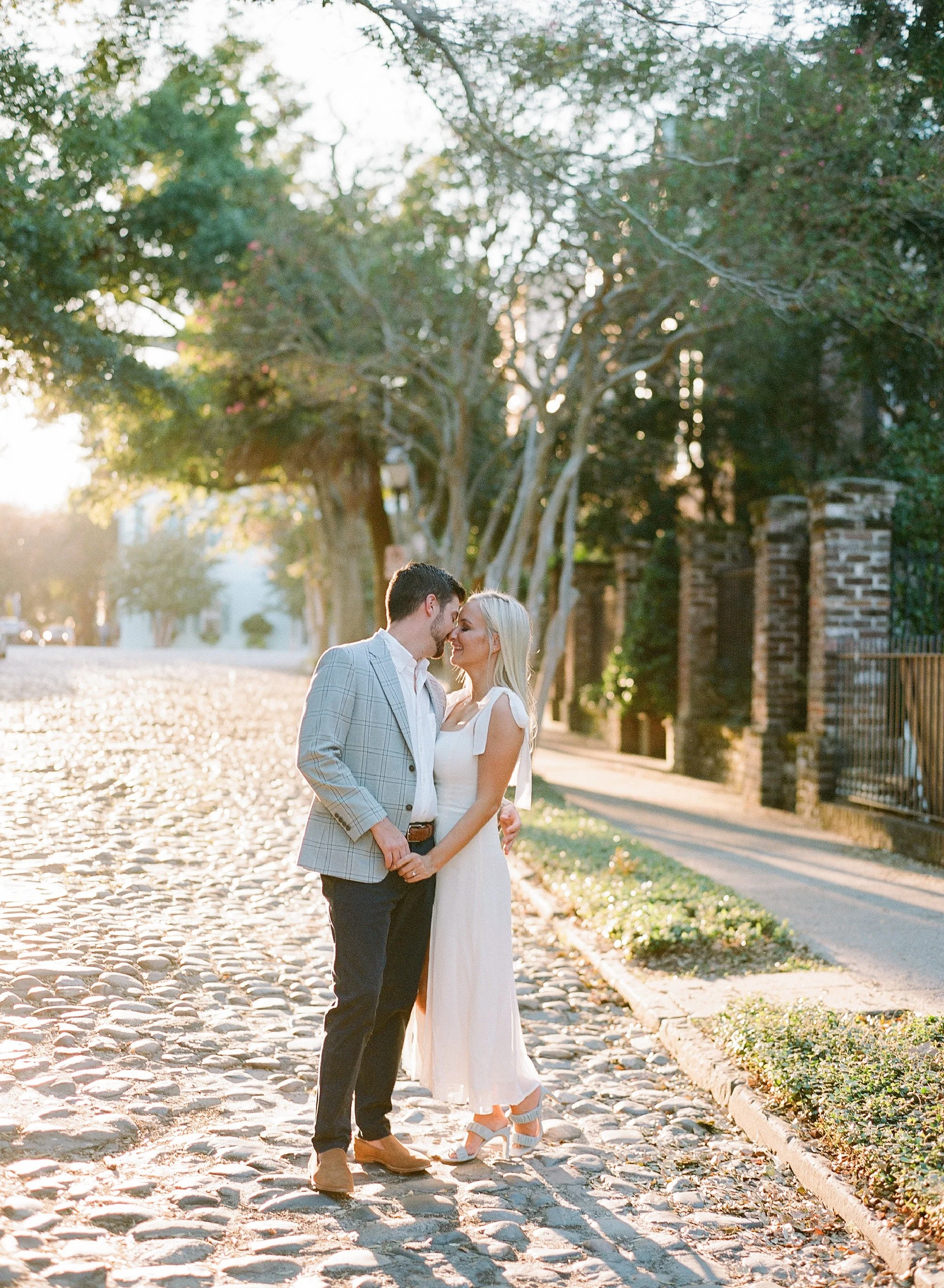 engagement photos on cobblestone at Adgers Wharf in Charleston with soft golden light