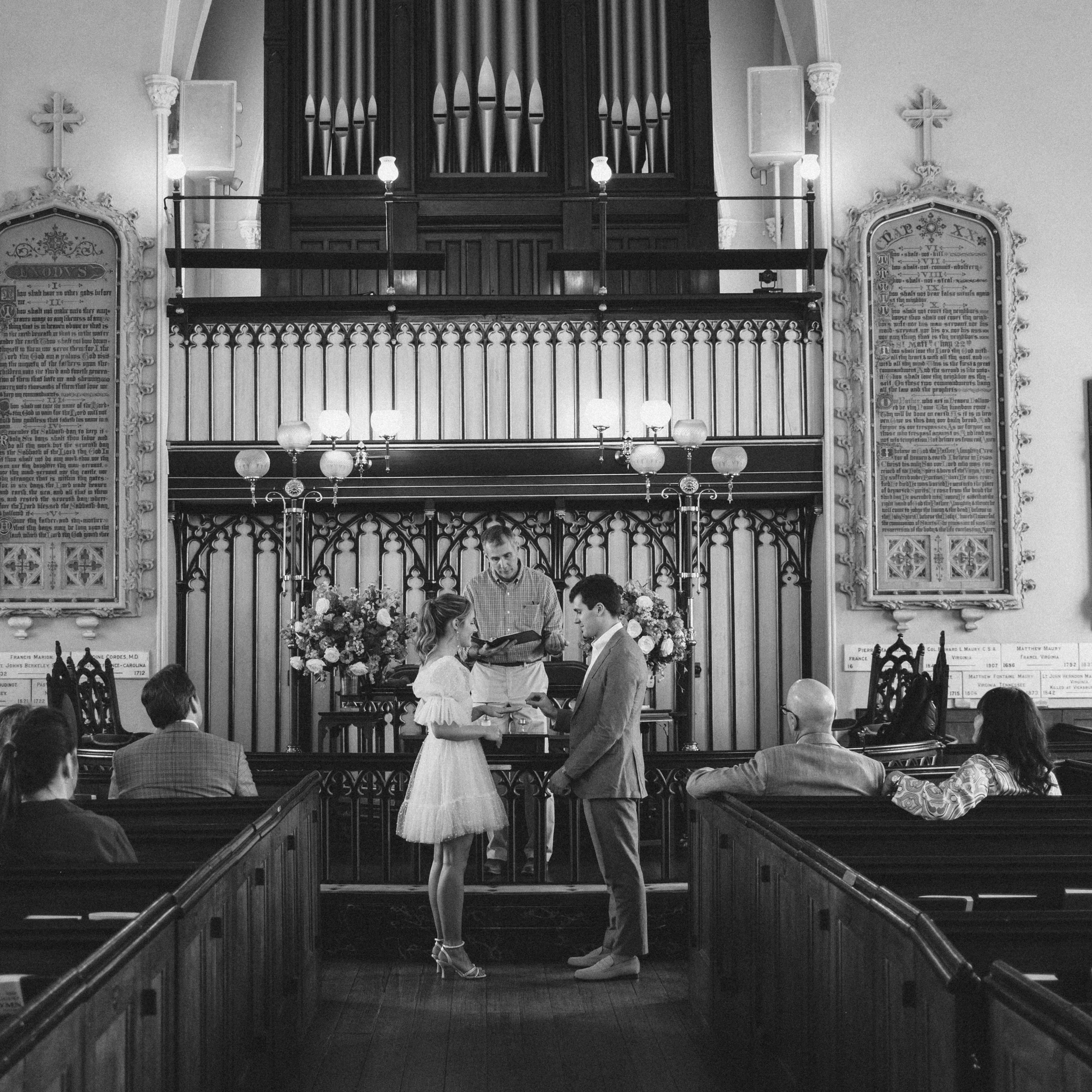 Wide black and white image of wedding ceremony inside the historic French Huguenot church