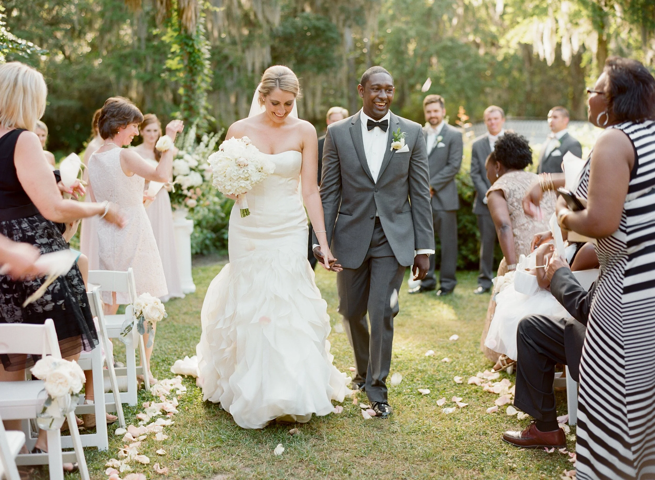 Charleston interracial wedding ceremony on film bride and groom walking down aisle with guests celebrating